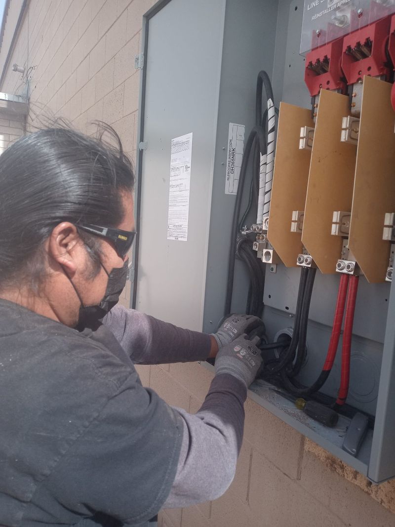 A man wearing a mask is working on an electrical box