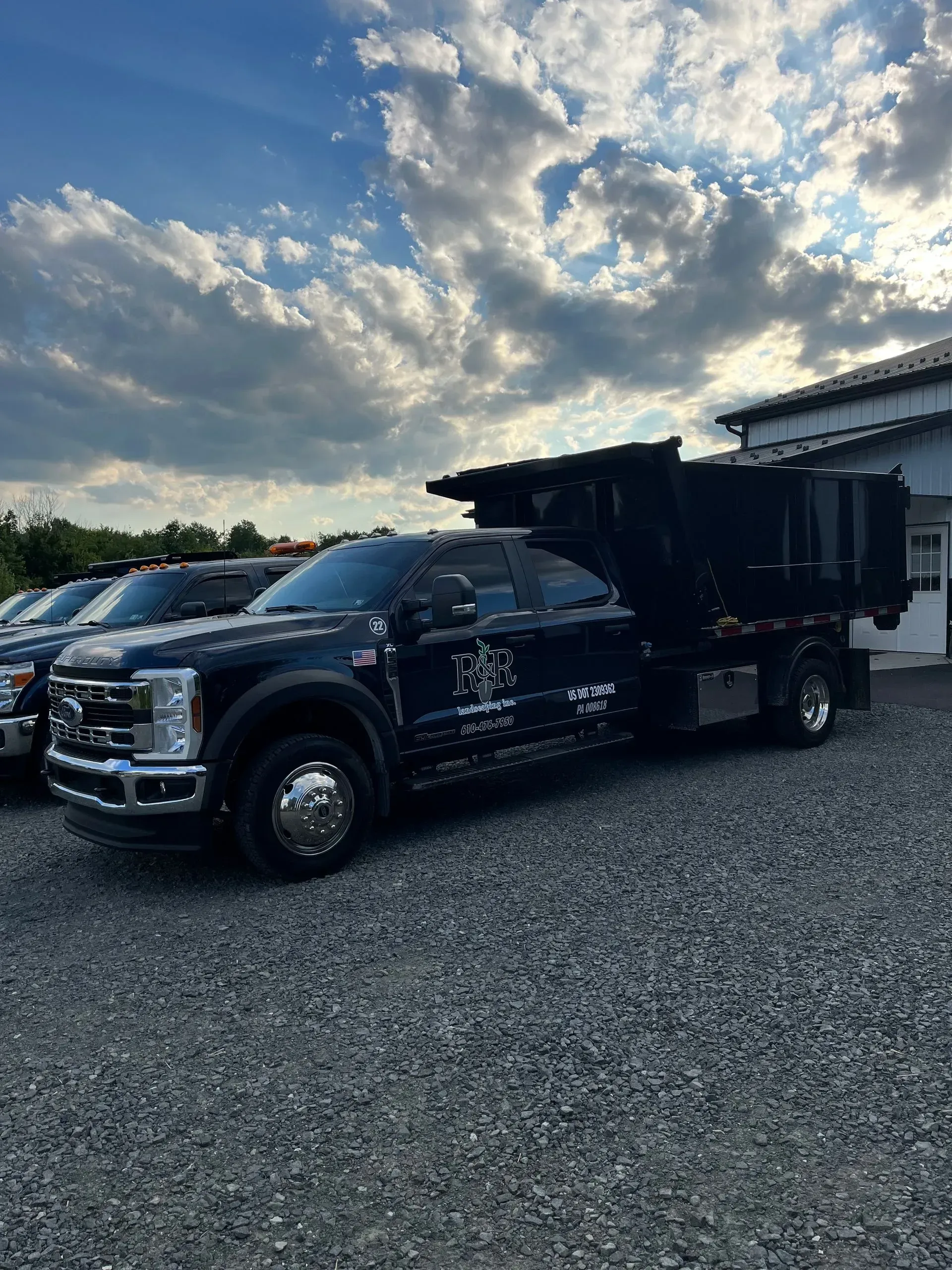 Black dump truck parked on gravel under a cloudy sky