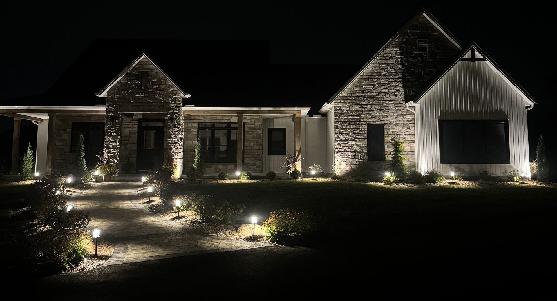 Landscaped front yard with gravel bed, stone walkway, and a white house entrance.