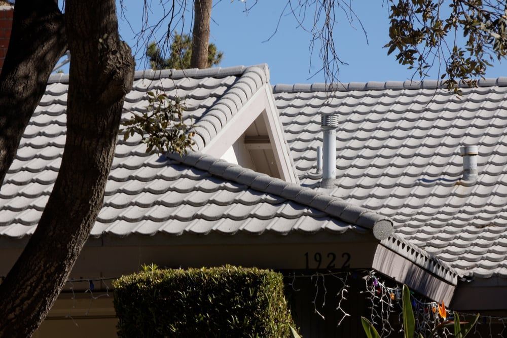 Gray tiled roof of a house with a chimney, visible numbers 