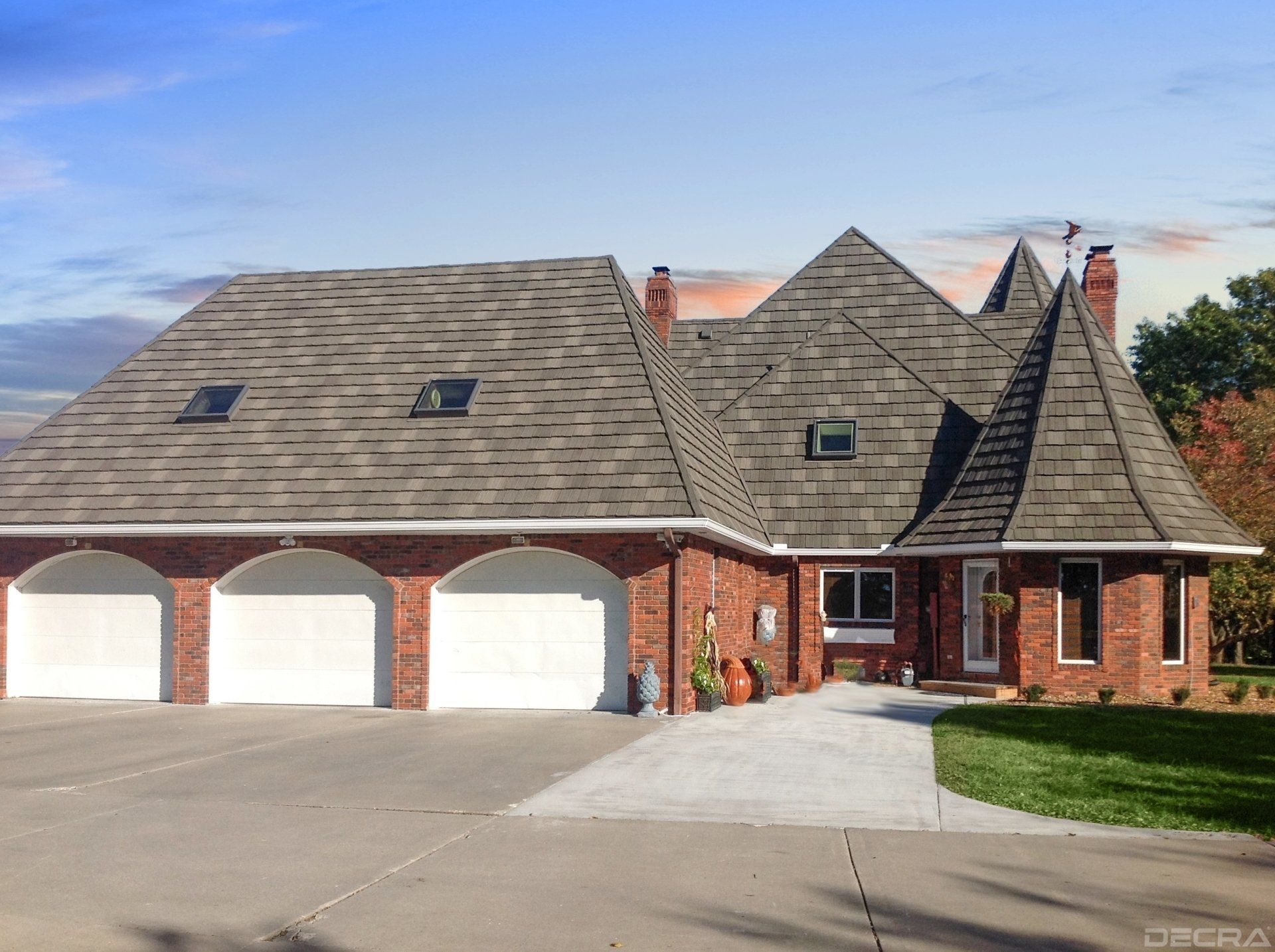 Brick home with three-car garage, accented by a turret. The roof is dark, and the sky is partly cloudy.