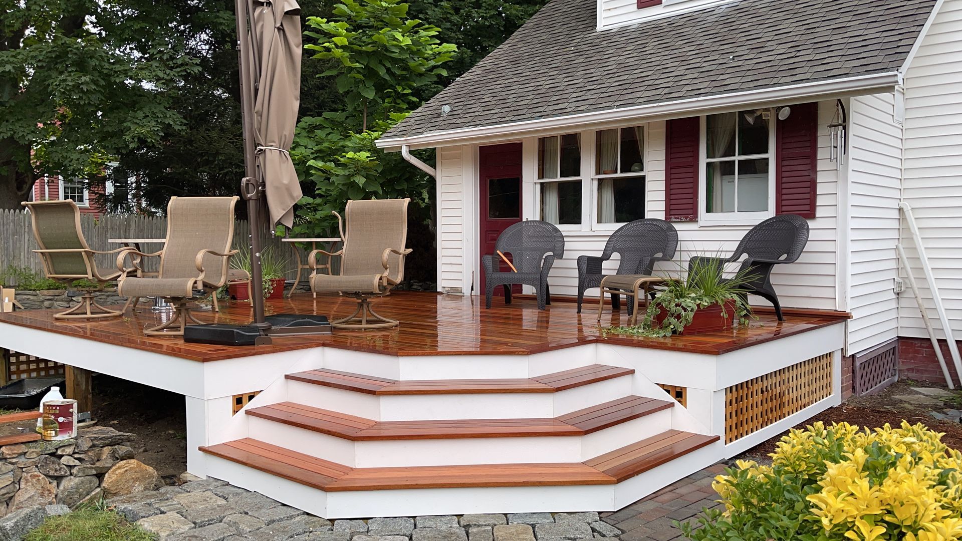 A white house with a wooden deck and chairs on it.