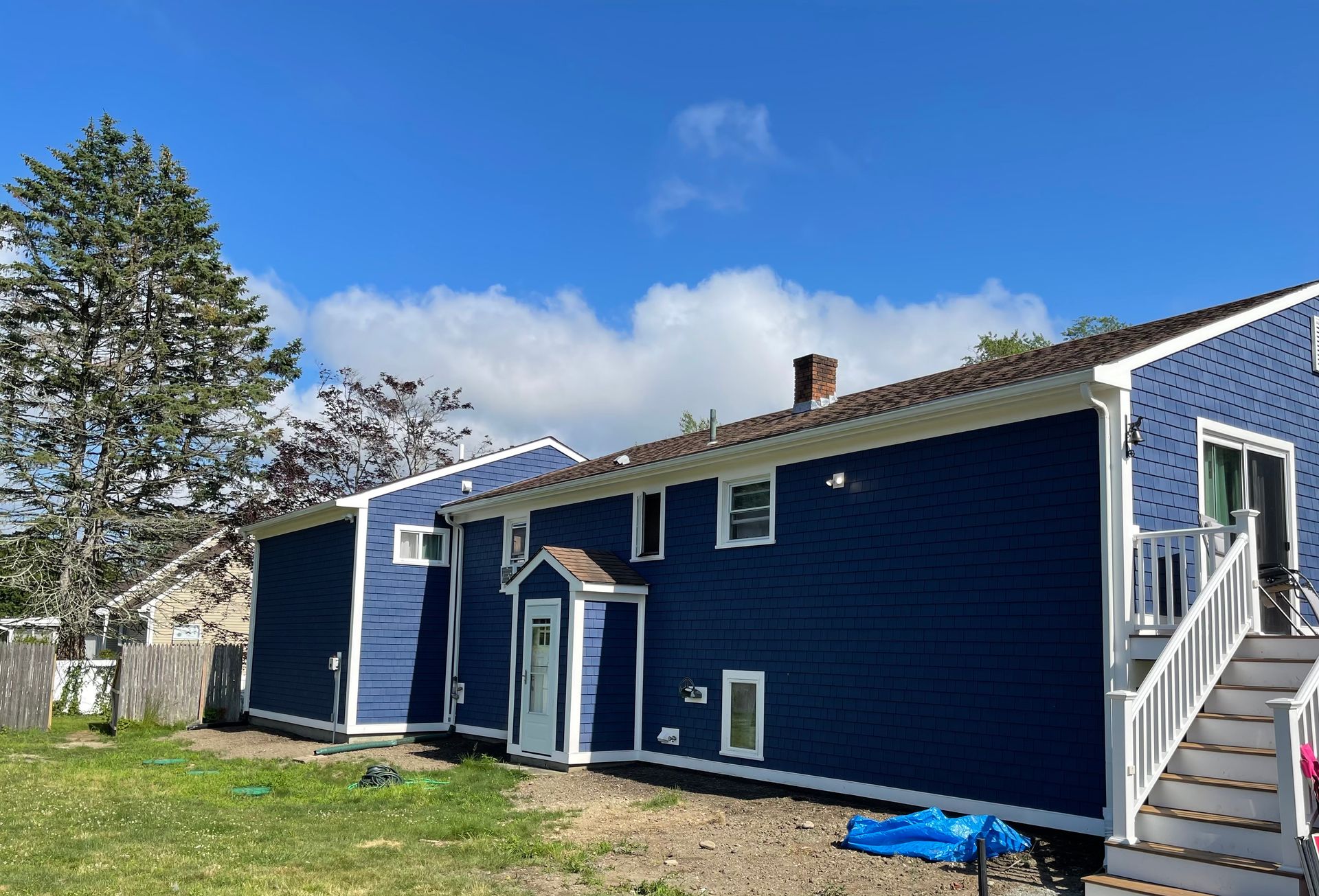 A blue house with white trim and stairs in the backyard.
