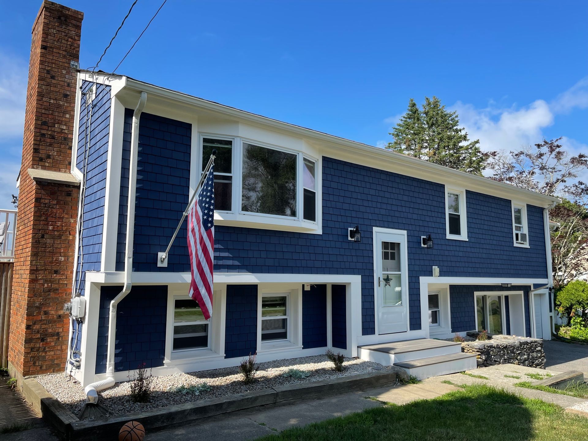 A blue house with an American flag hanging from the side of it.