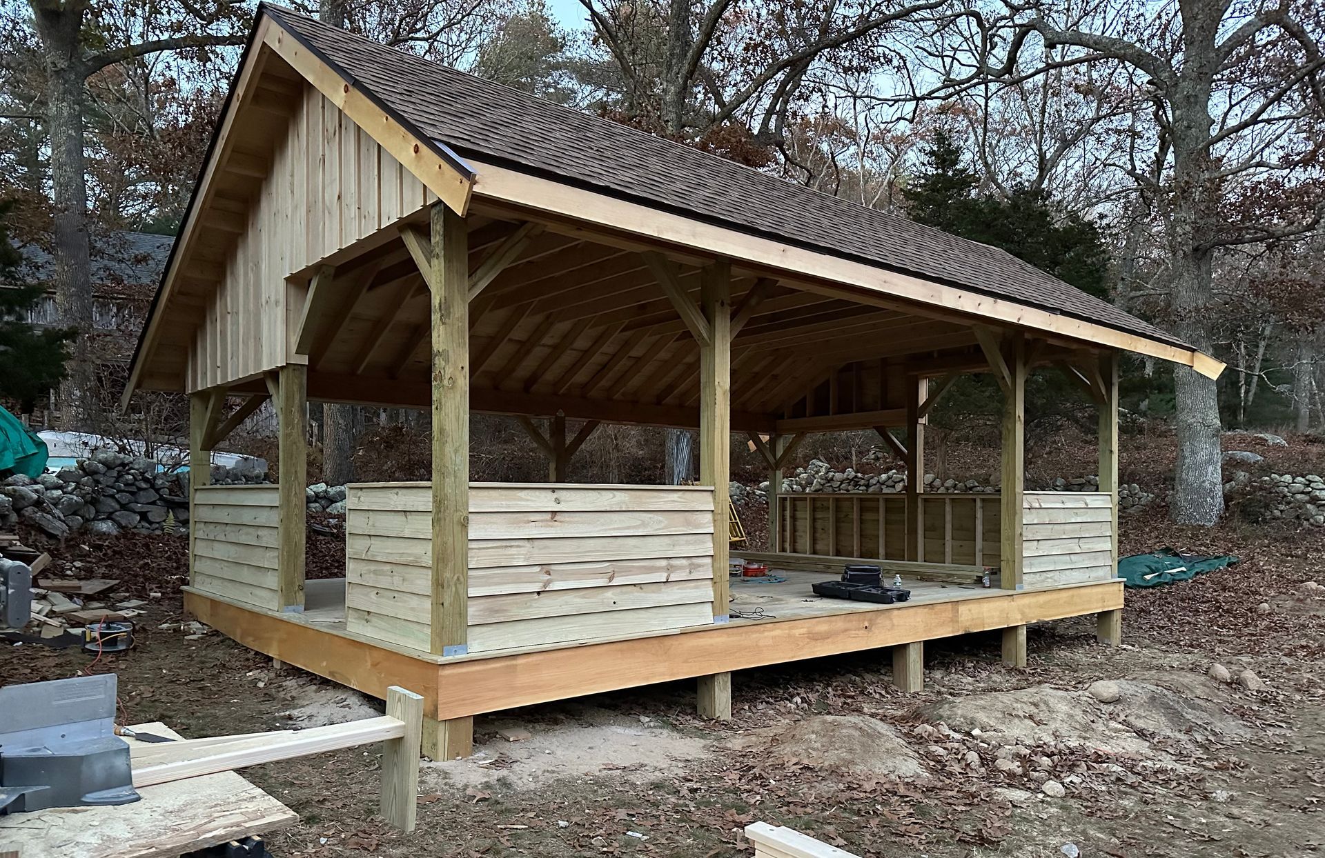 A wooden pavilion is being built in the woods.