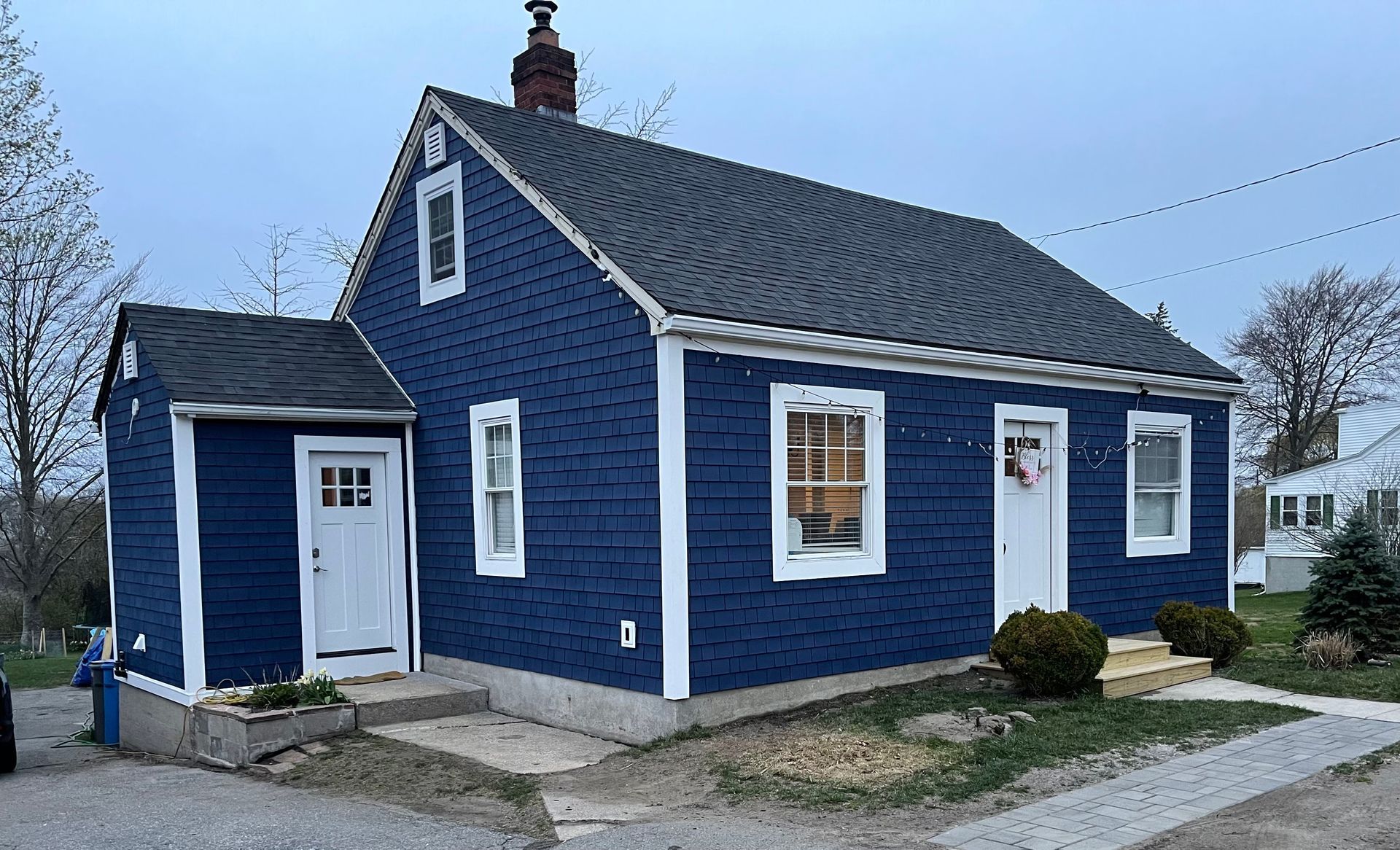 A small blue house with white trim and a black roof.