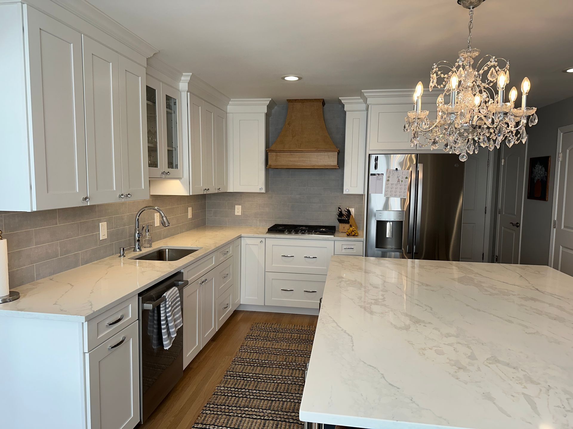 A kitchen with white cabinets and a large island with a chandelier hanging from the ceiling.
