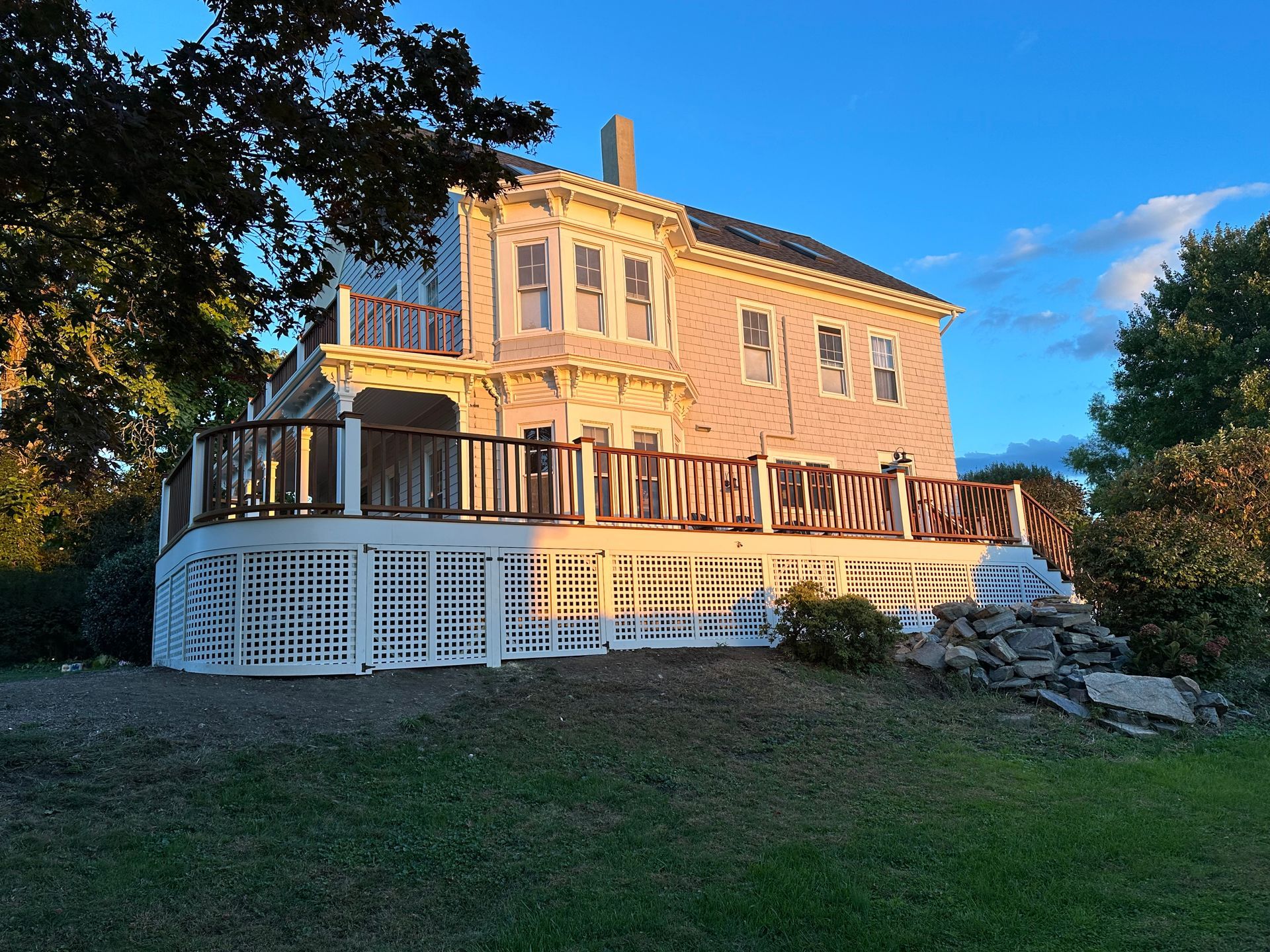 A large pink house with a large deck in front of it.