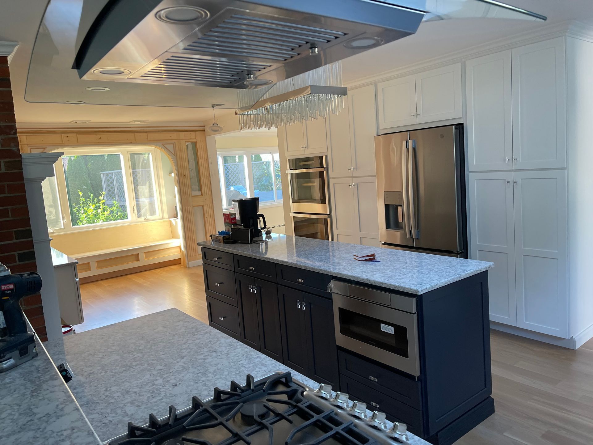 A kitchen with a large island, stove, refrigerator, and microwave.