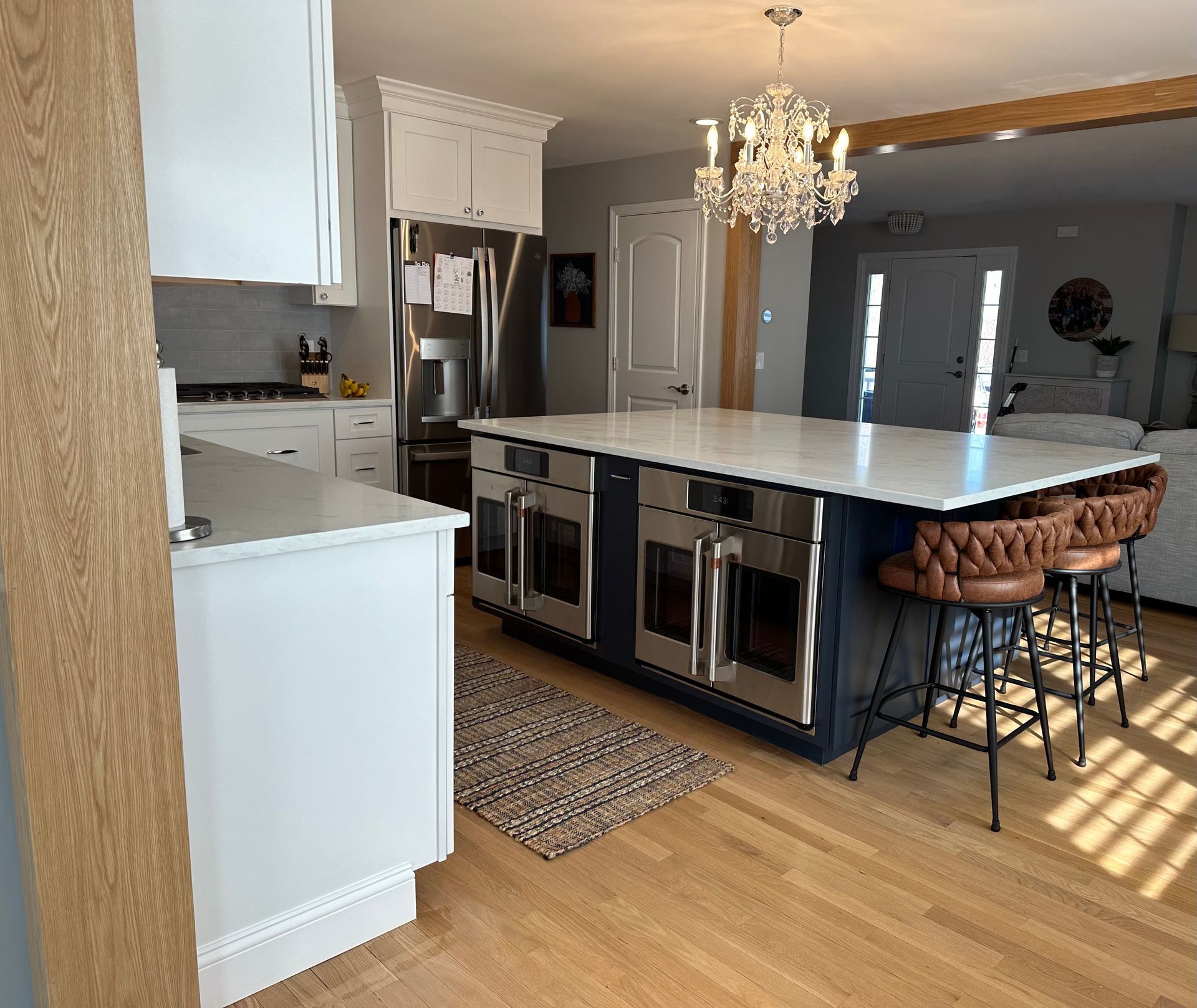 A kitchen with a large island, stools, and a chandelier.