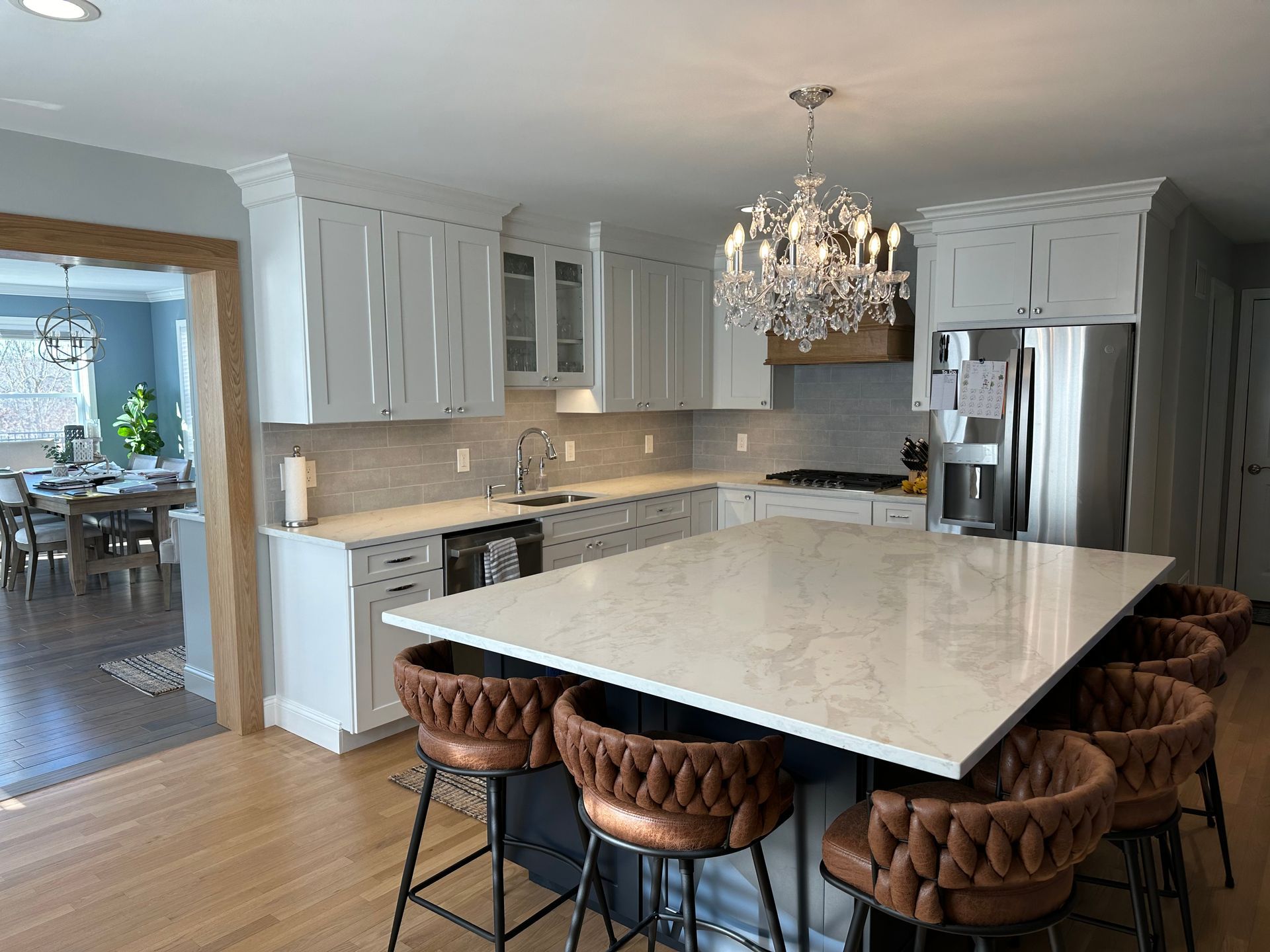A kitchen with a large island in the middle and a chandelier hanging from the ceiling.