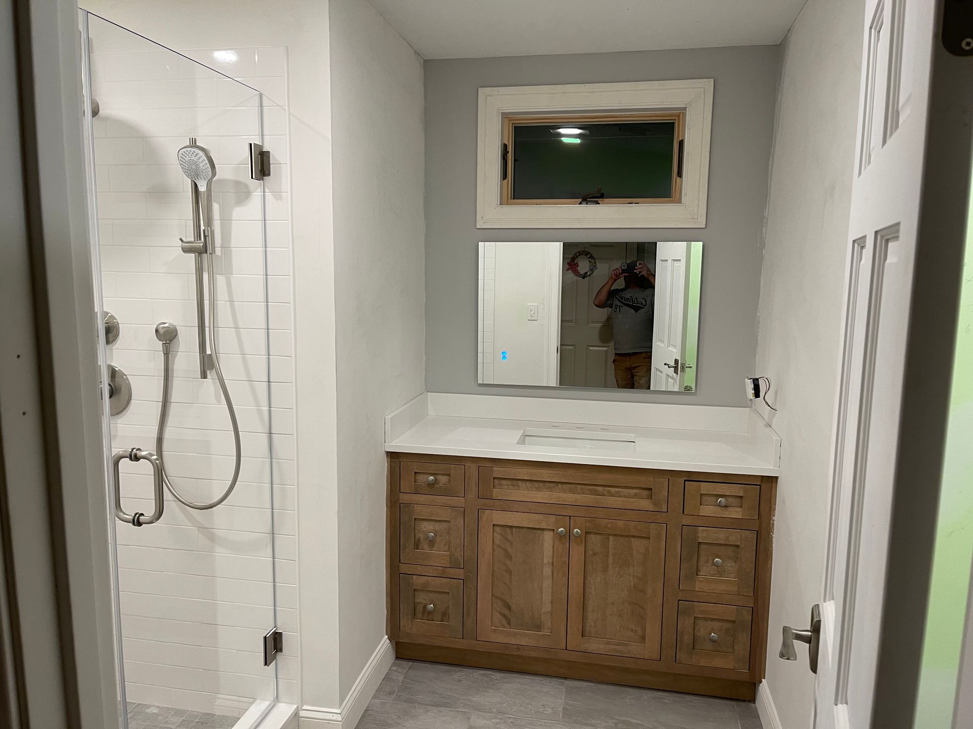 A bathroom with a sink, shower, and mirror.