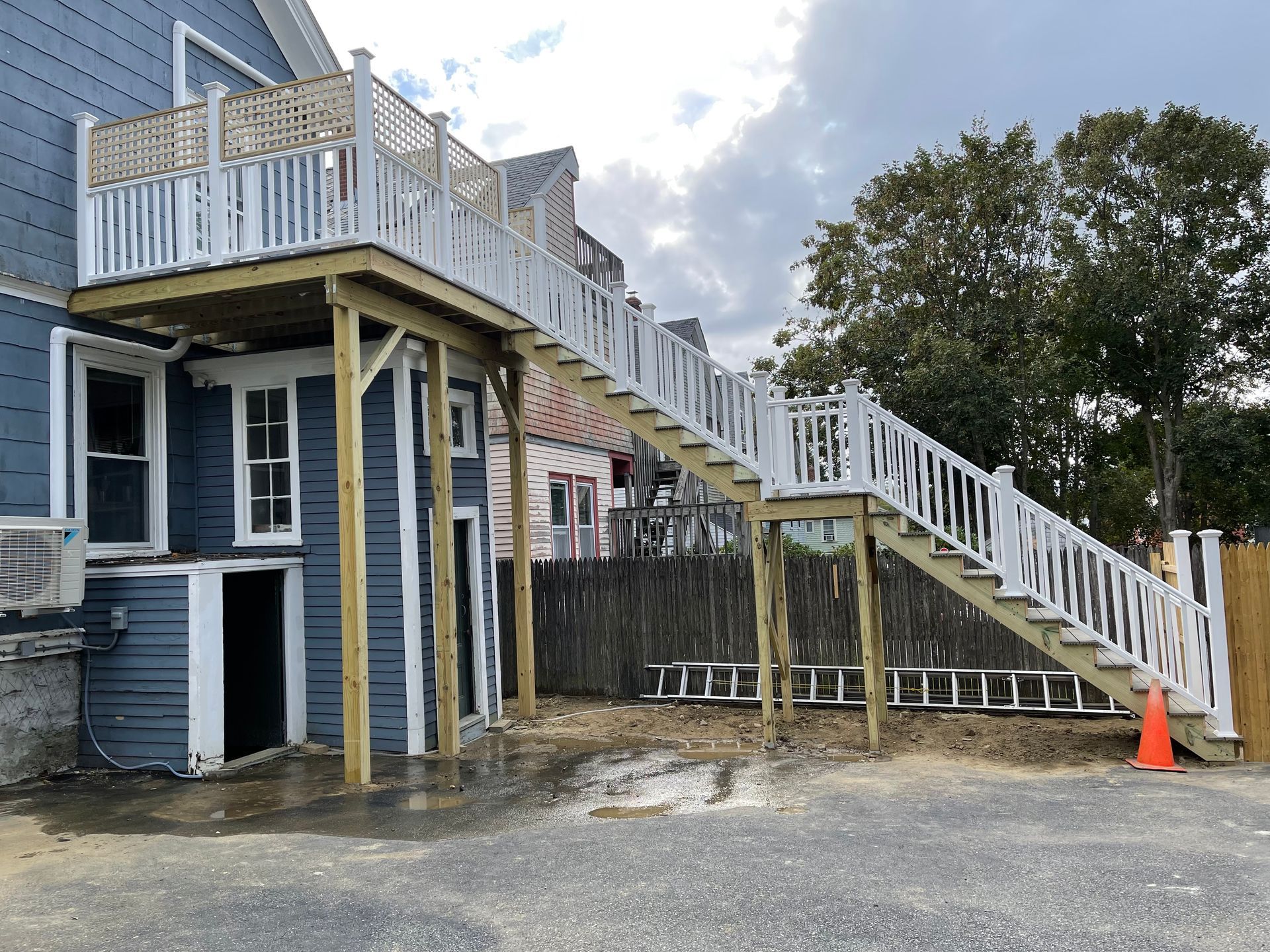 A wooden deck with stairs leading up to it is being built on the side of a house.