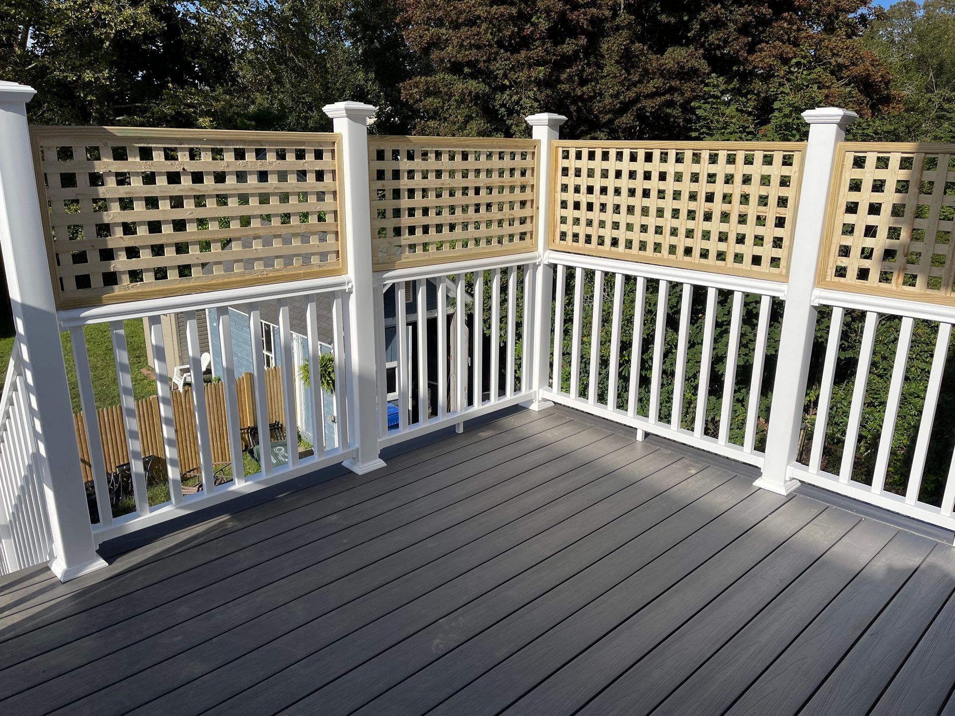A deck with a white railing and a wooden fence.