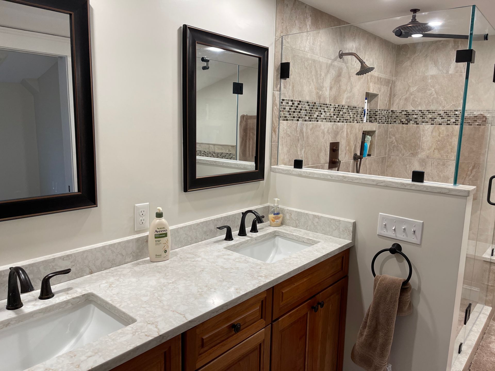 A bathroom with two sinks, two mirrors, and a walk-in shower.