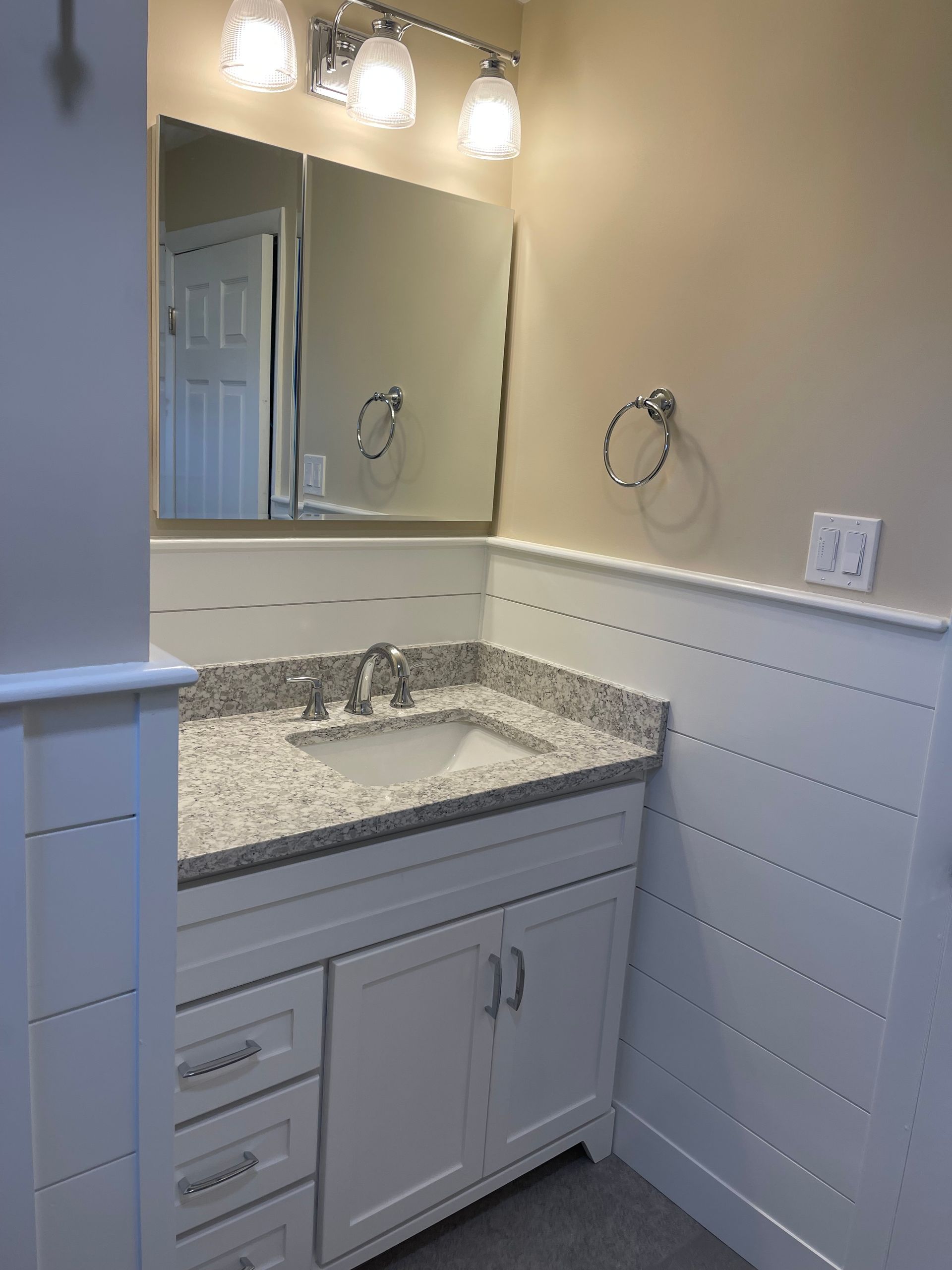 A bathroom with a sink, mirror, and cabinets.
