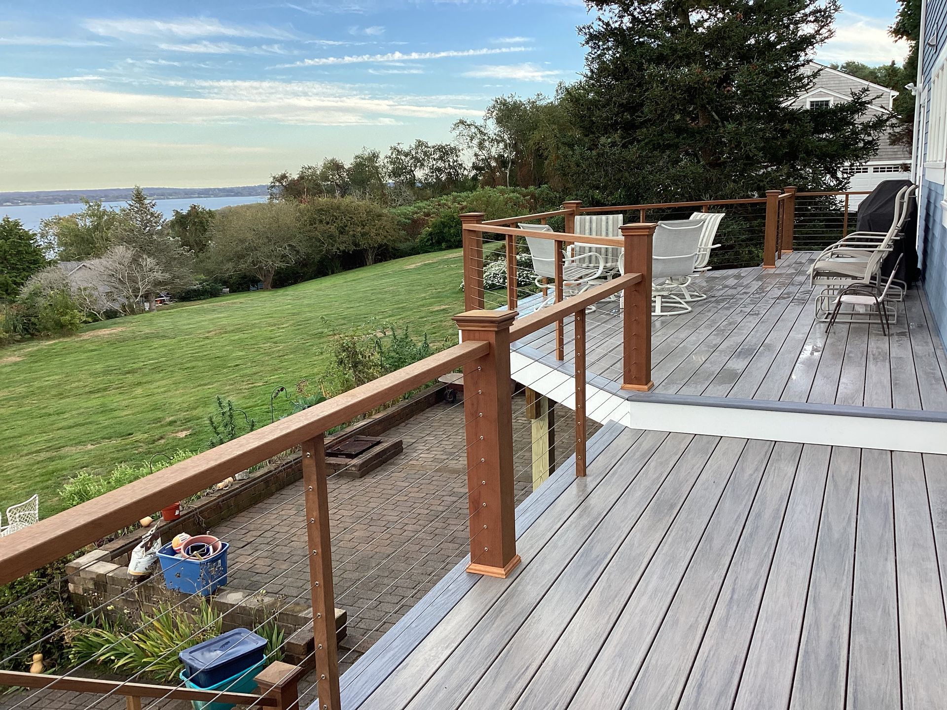A deck with a view of a field and a lake.