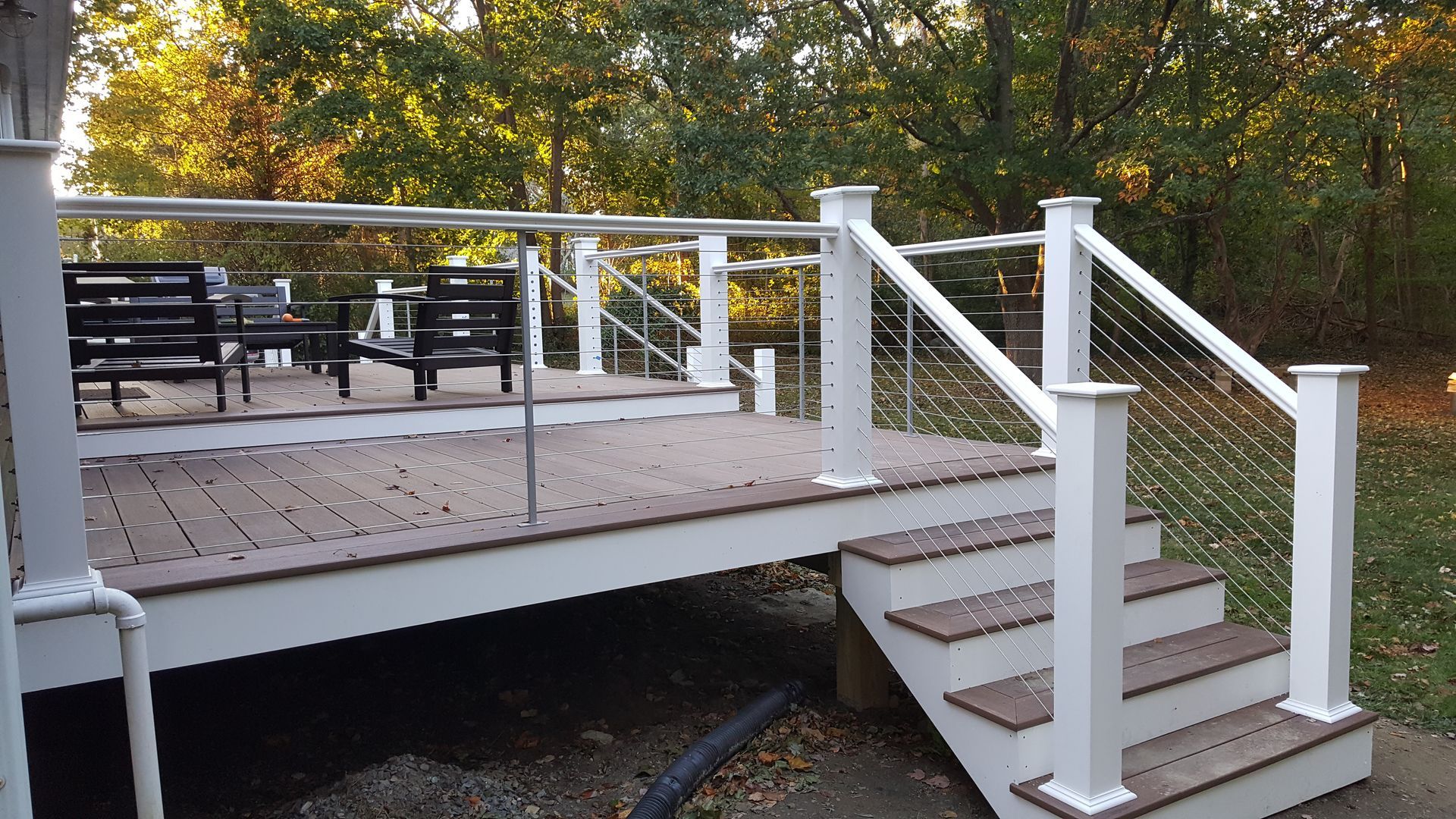 A white deck with stairs and a stainless steel railing.