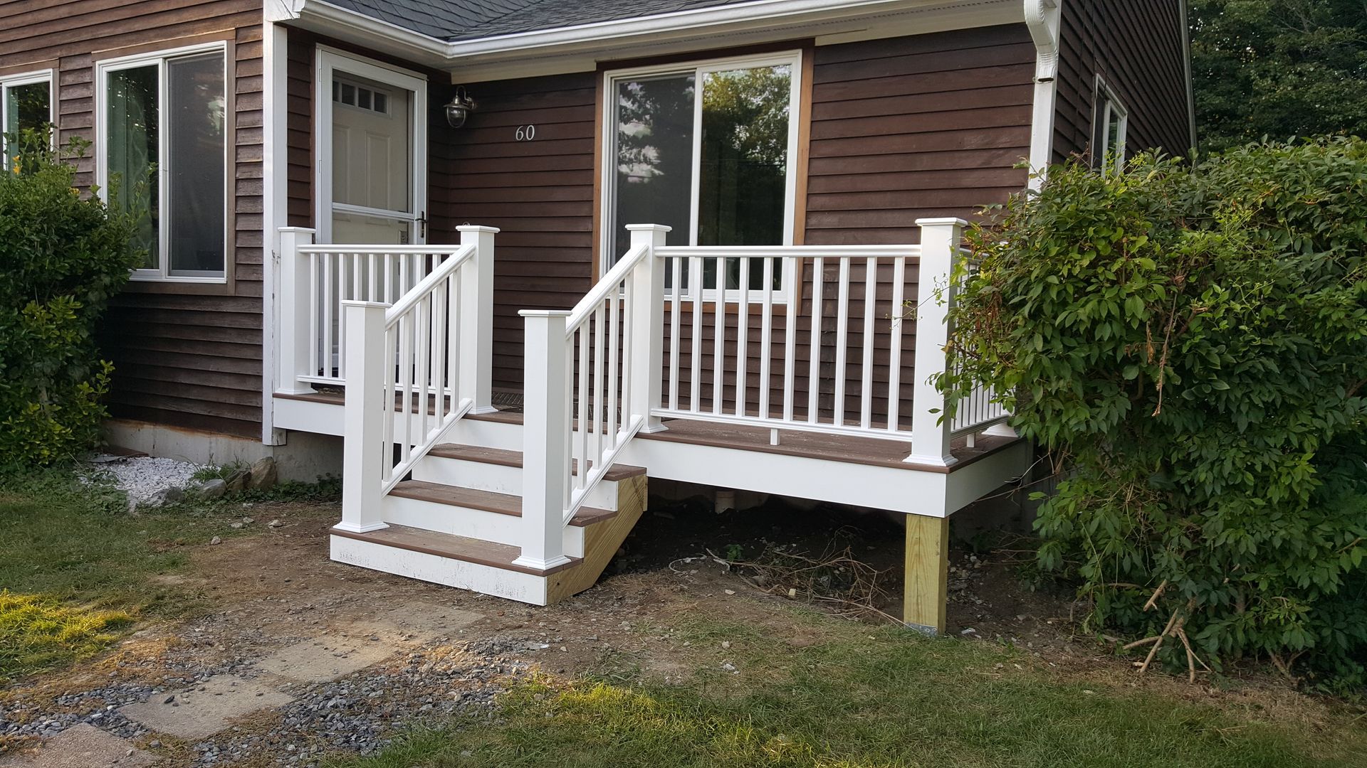 A brown house with a white porch and stairs.