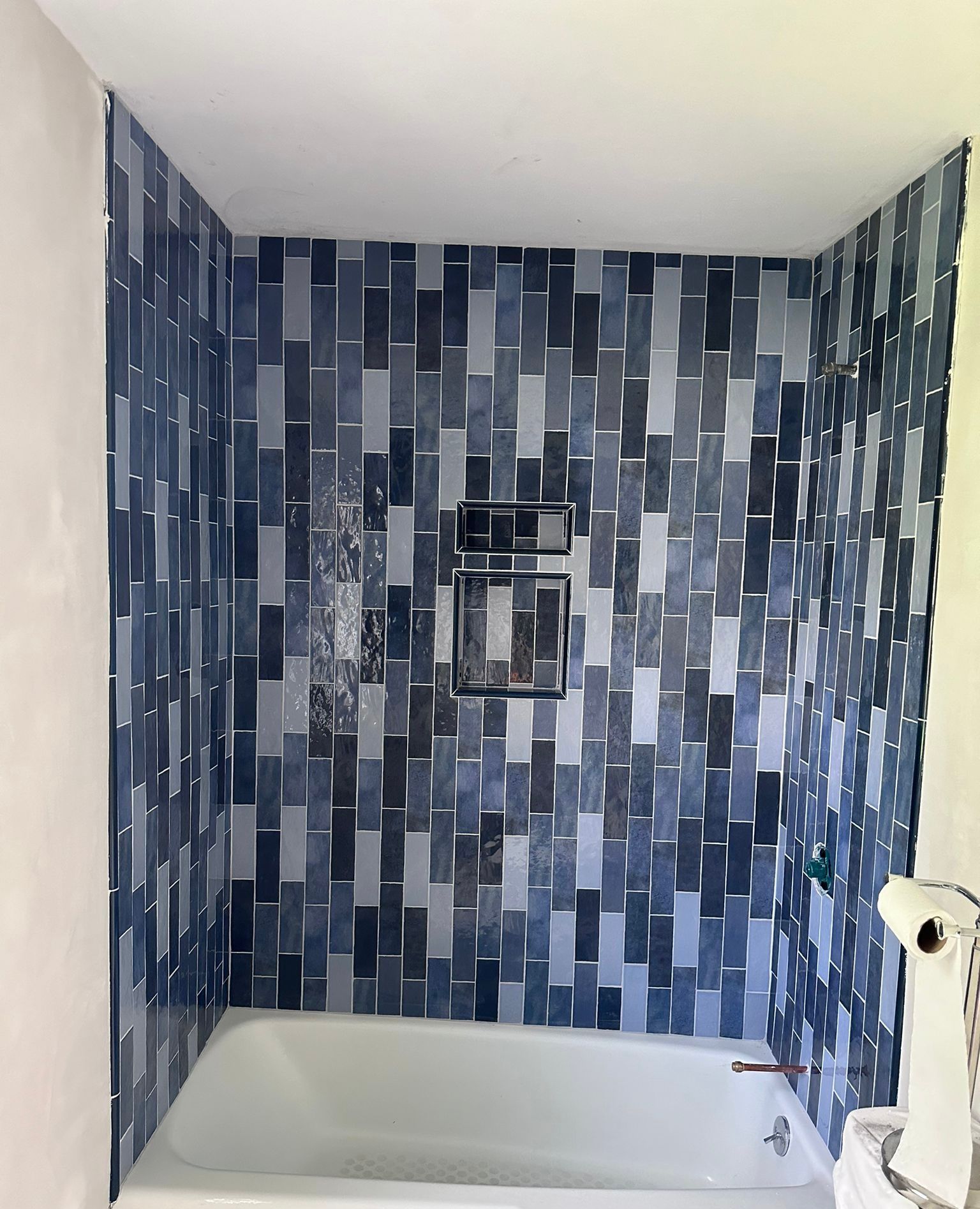 A bathroom with blue tiles and a bathtub.