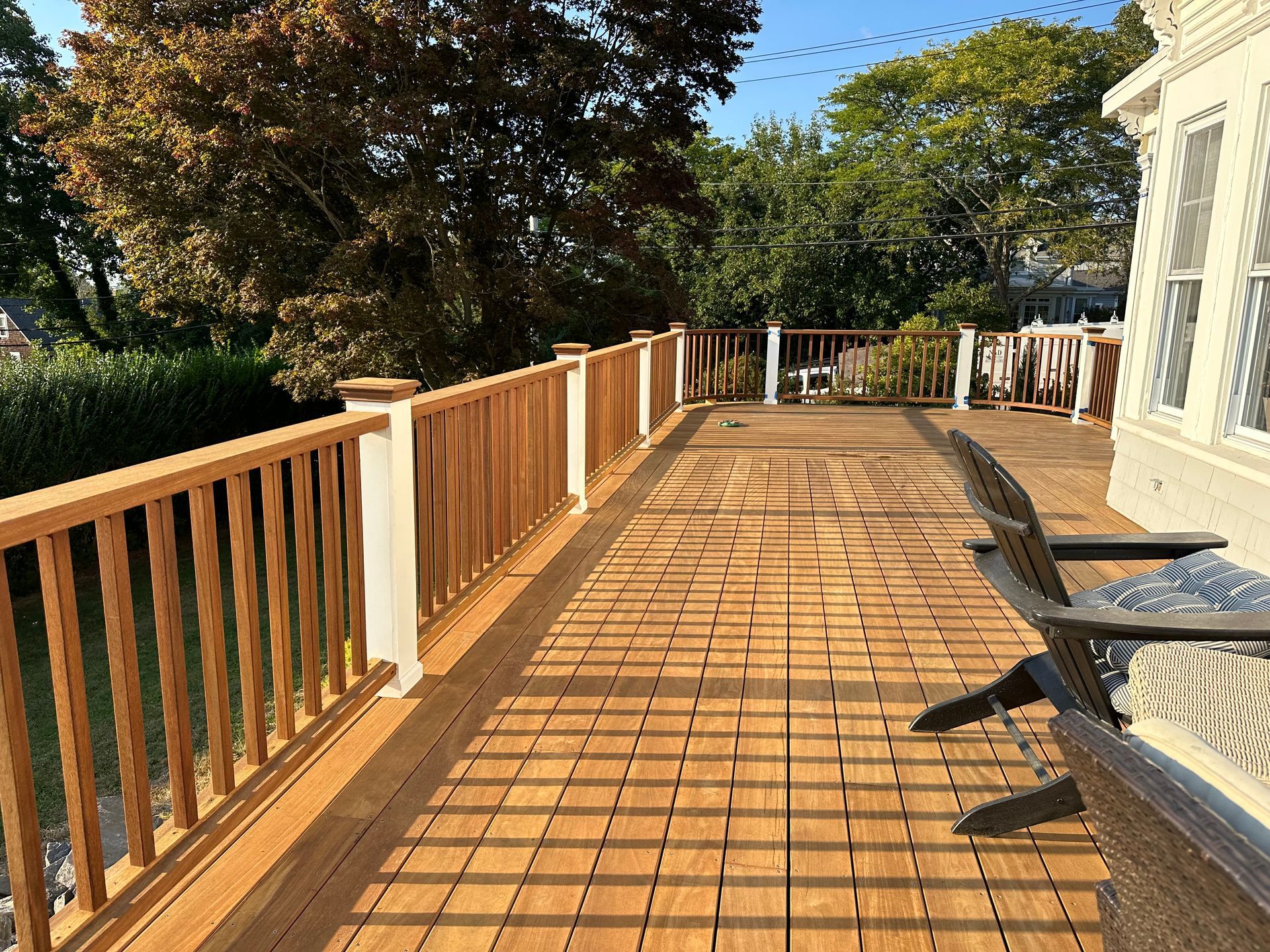 A large wooden deck with a wooden railing and chairs.