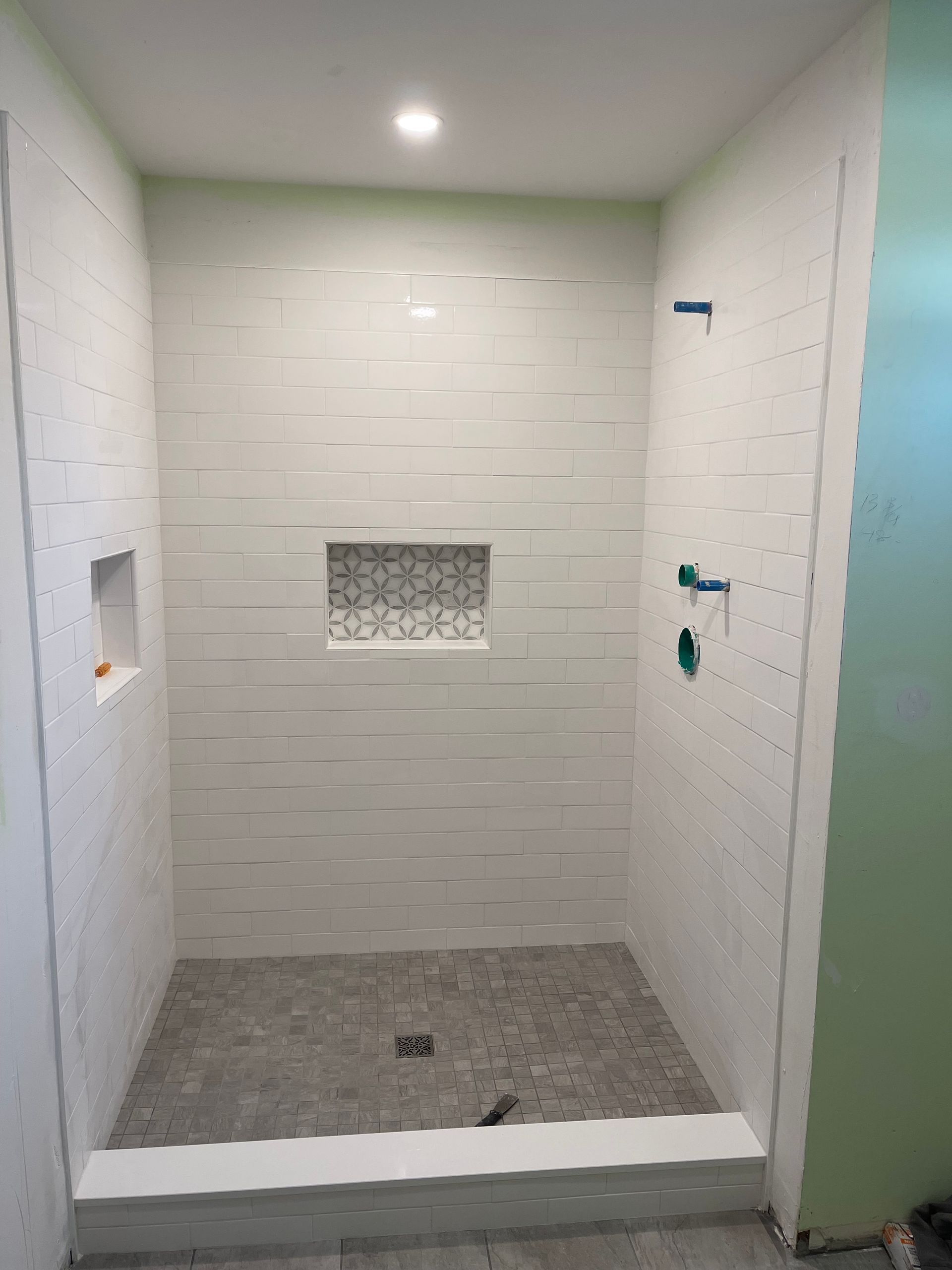 A shower stall with white tiles and a niche in the wall.
