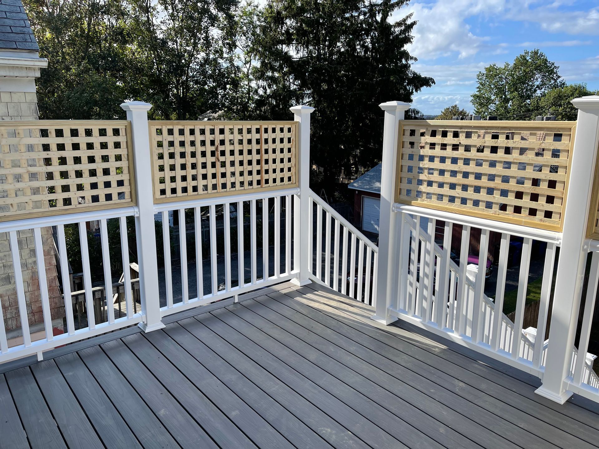 A deck with a white railing and a wooden trellis.
