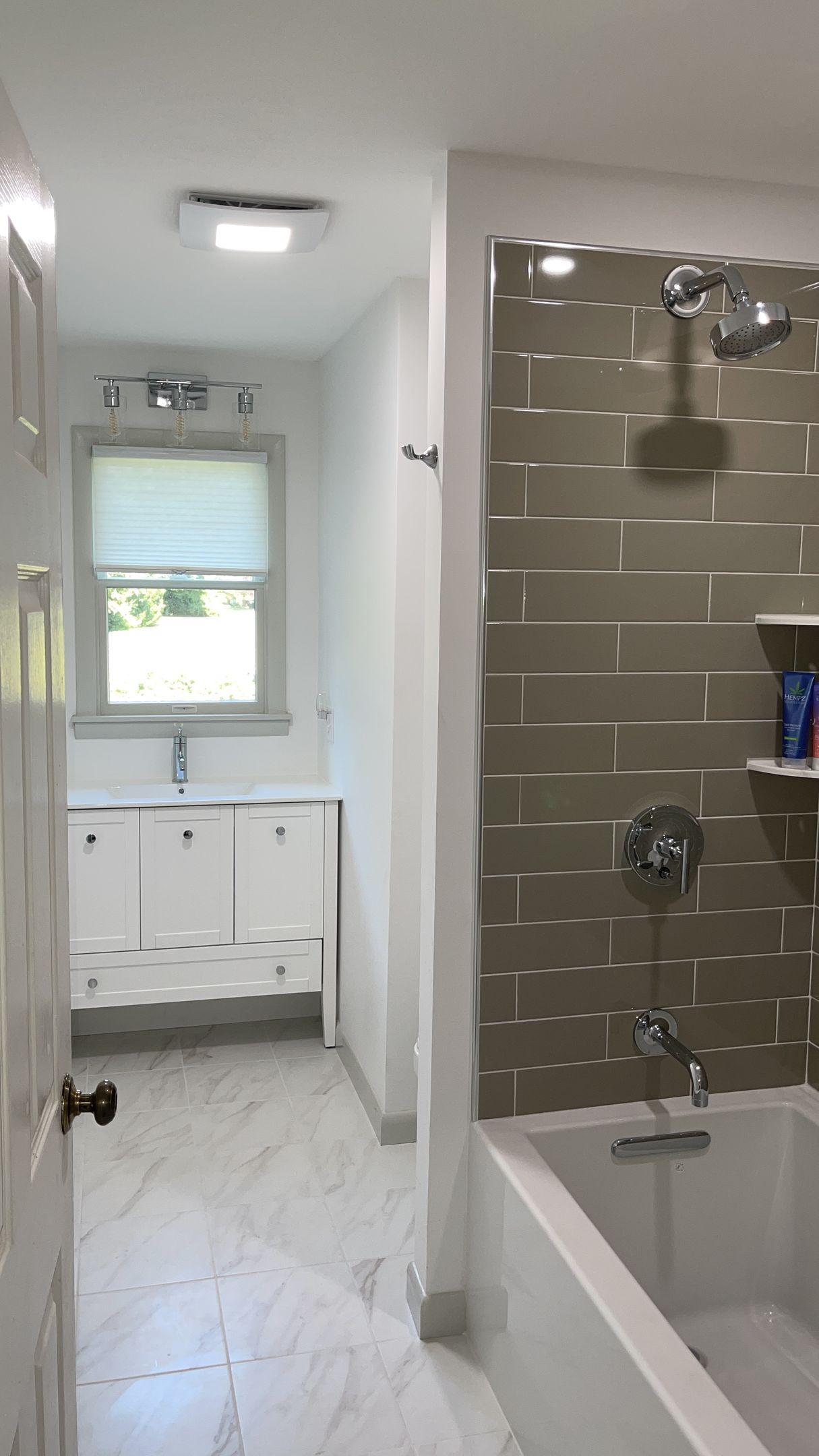 A bathroom with a tub, sink, shower and window.