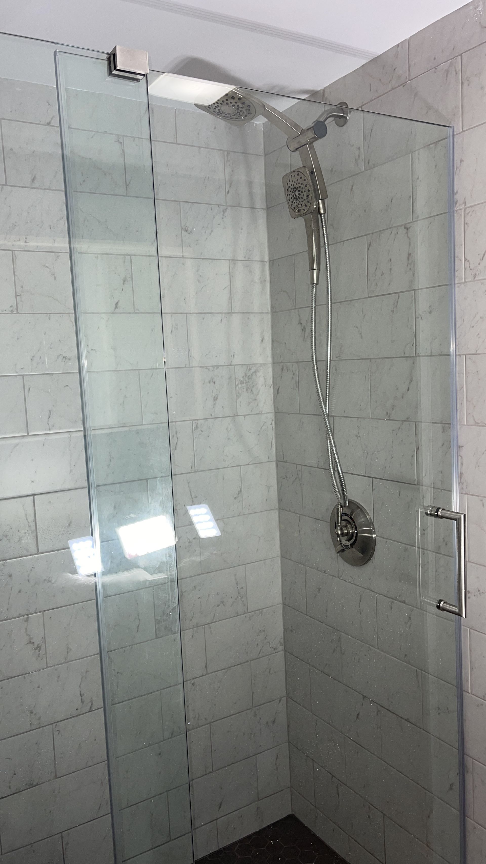 A shower stall with a glass door and a shower head.