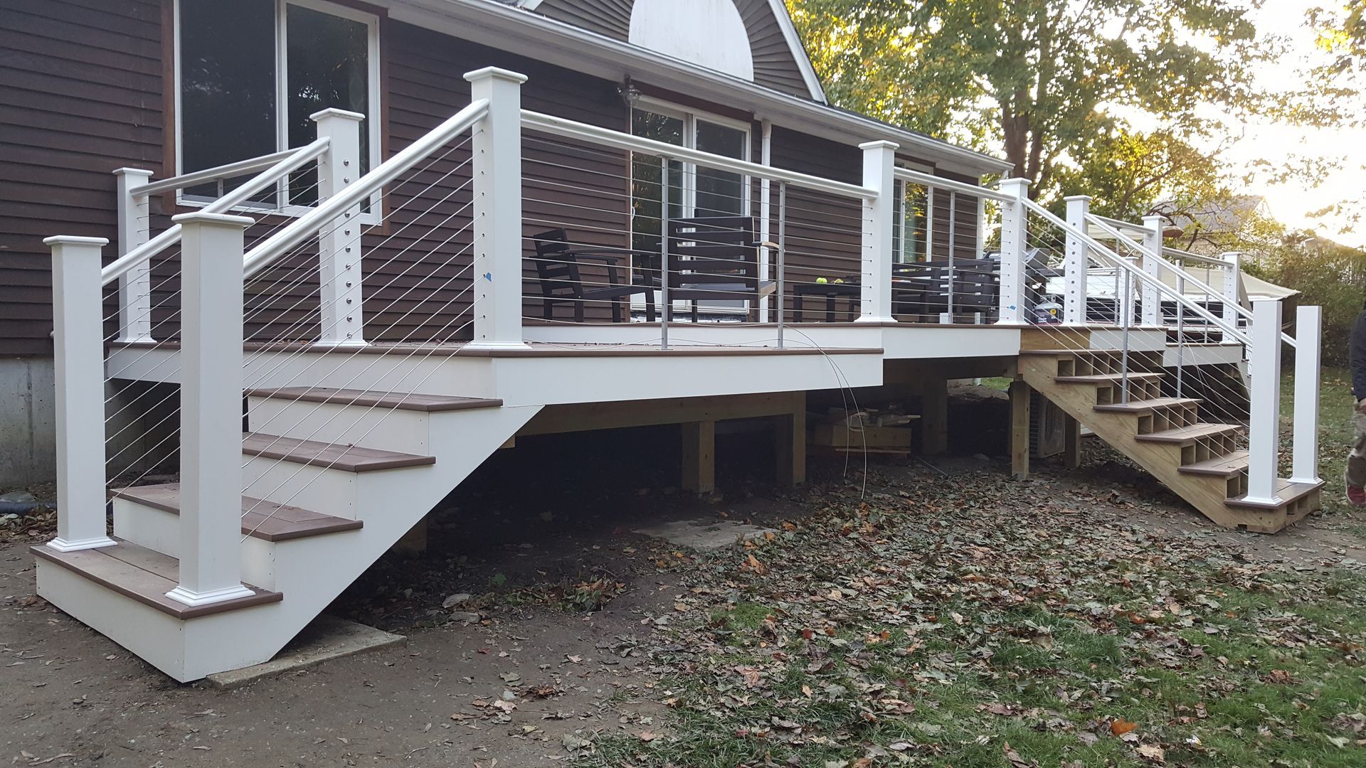 A large deck with stairs leading up to it is in front of a house.