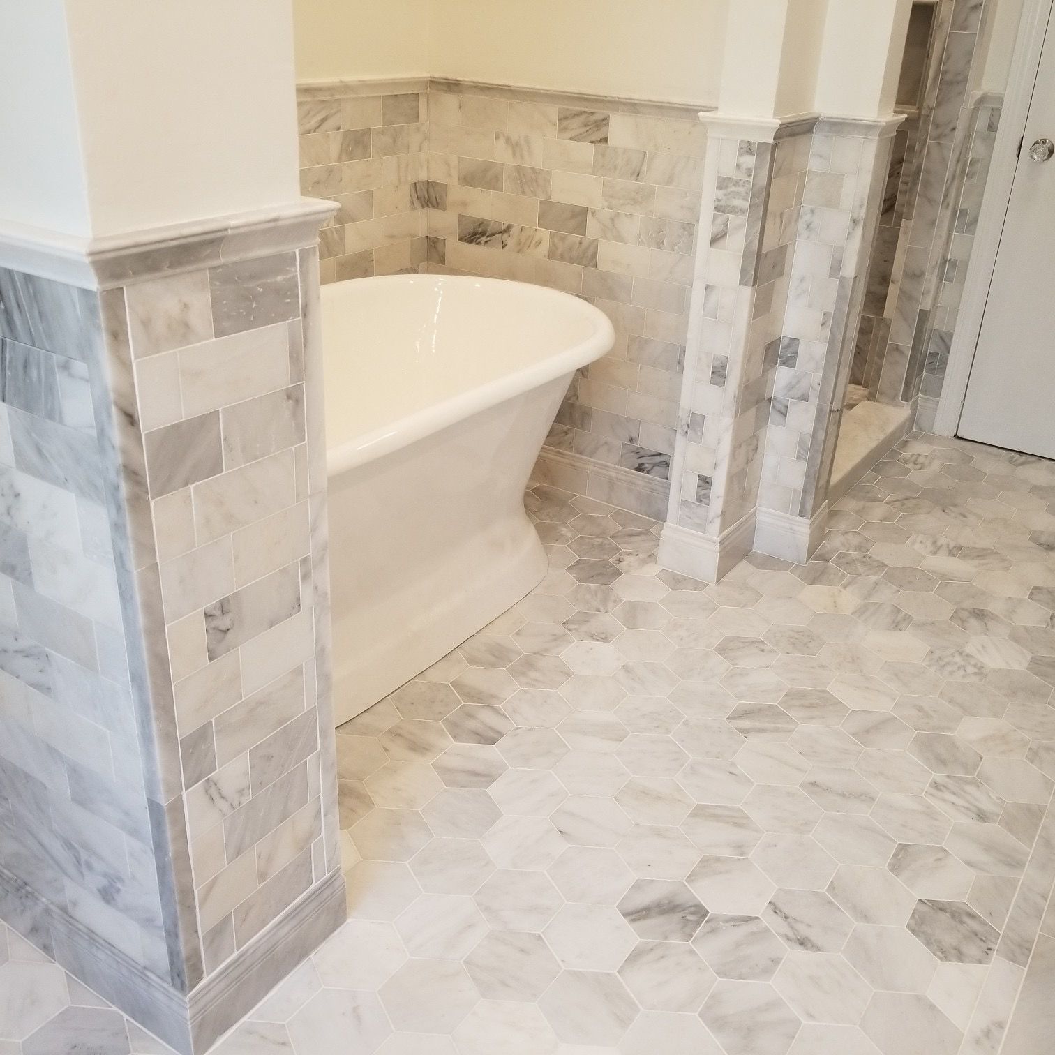 A bathroom with a tub and a tiled floor.