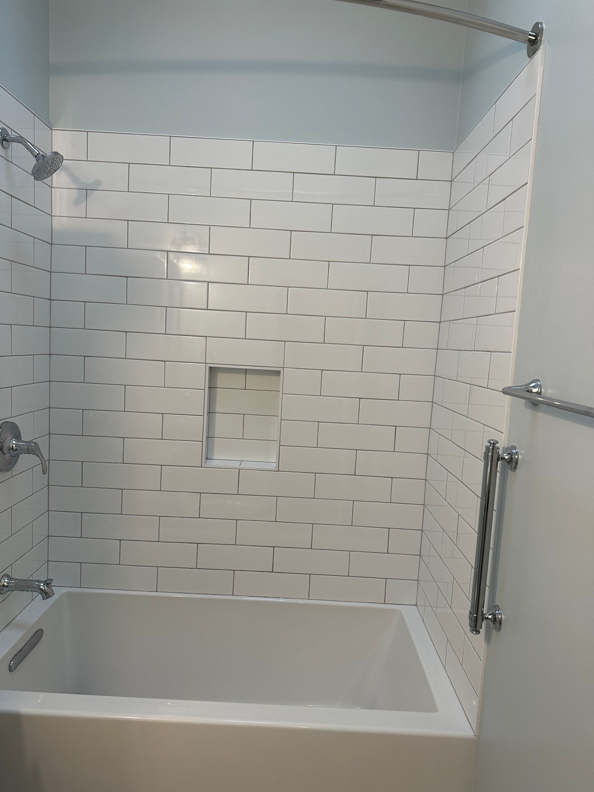 A bathroom with a bathtub and a shower with white tiles.