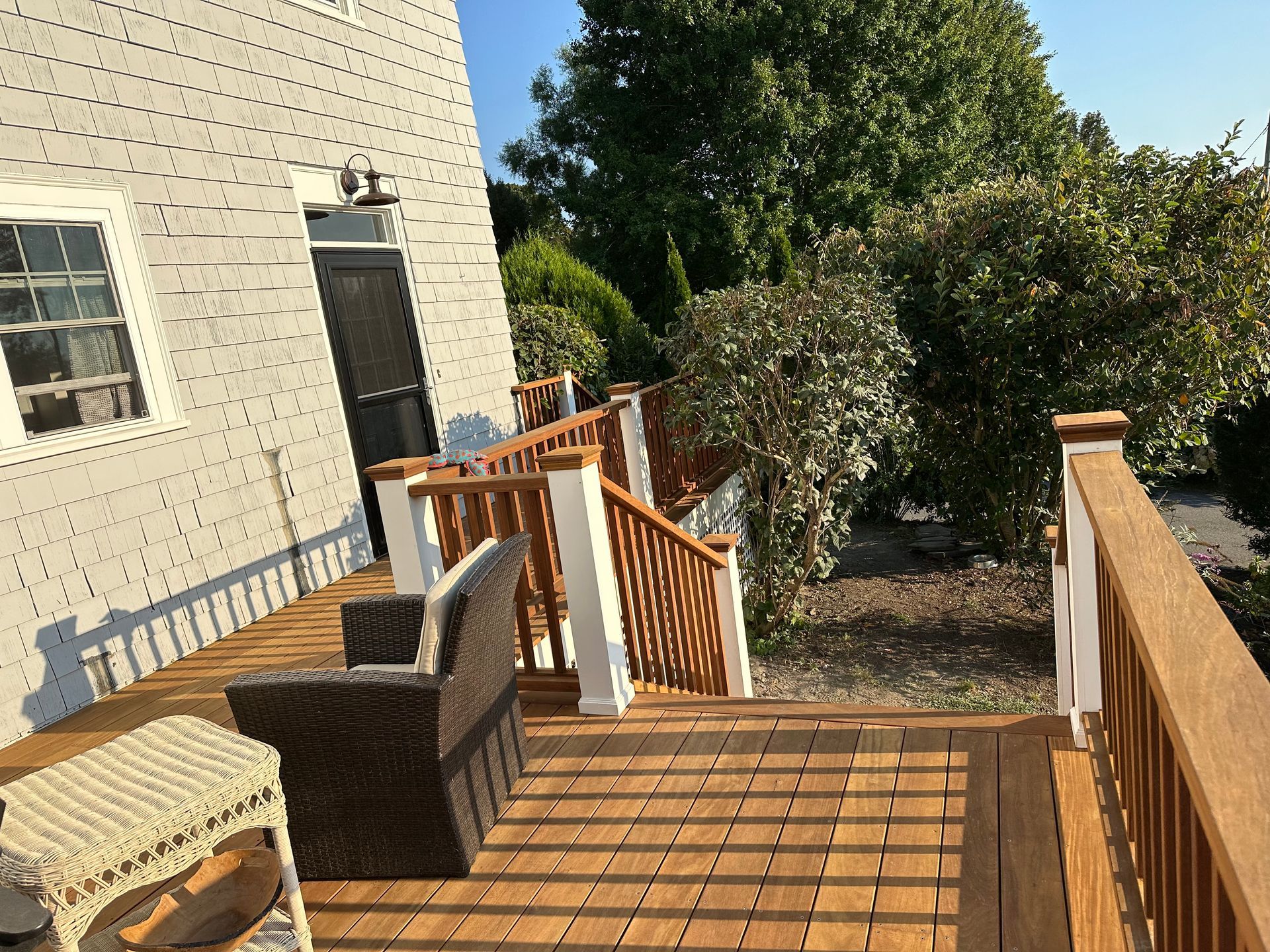 A white house with a wooden deck and stairs.