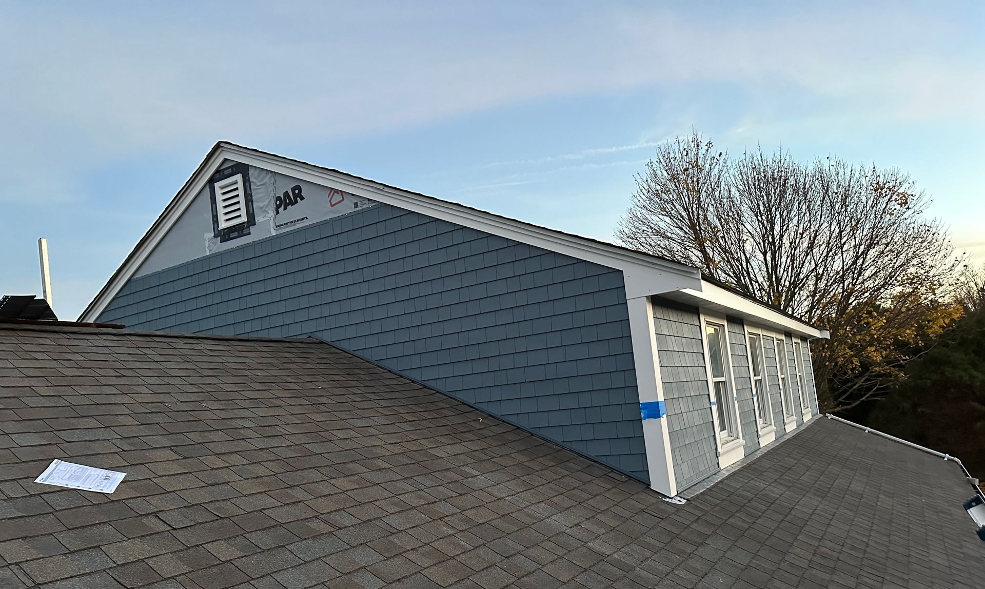 A garage with a roof is being built and a blue sky is in the background.