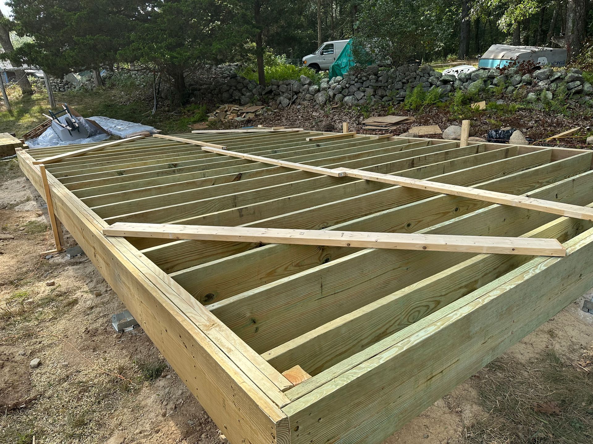 A wooden deck is being built on a dirt field.