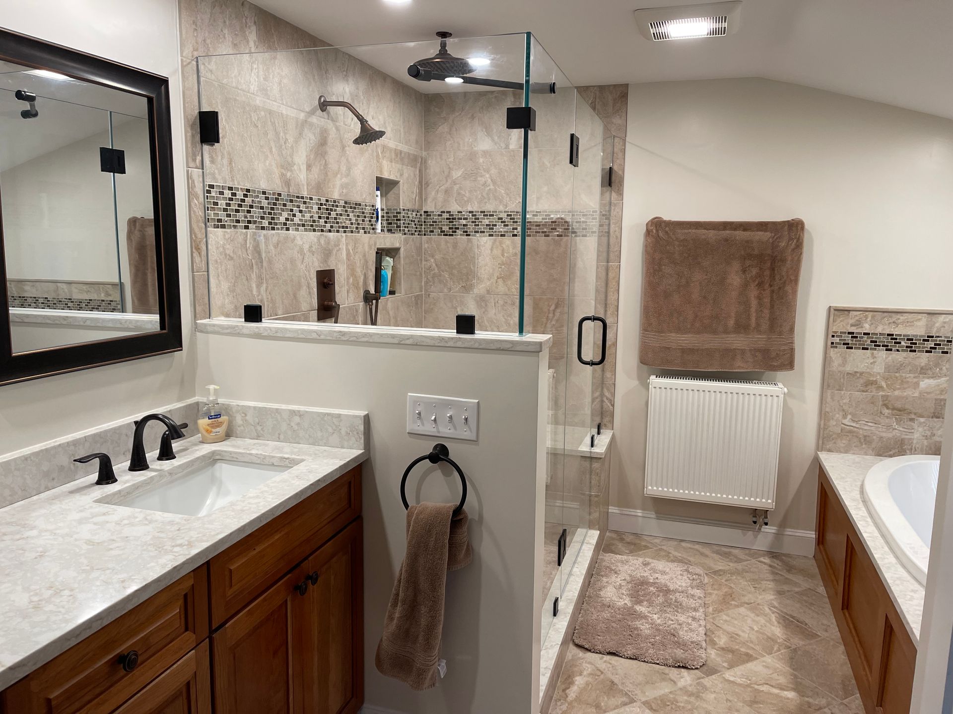 A bathroom with a walk-in shower, sink, mirror, and tub.