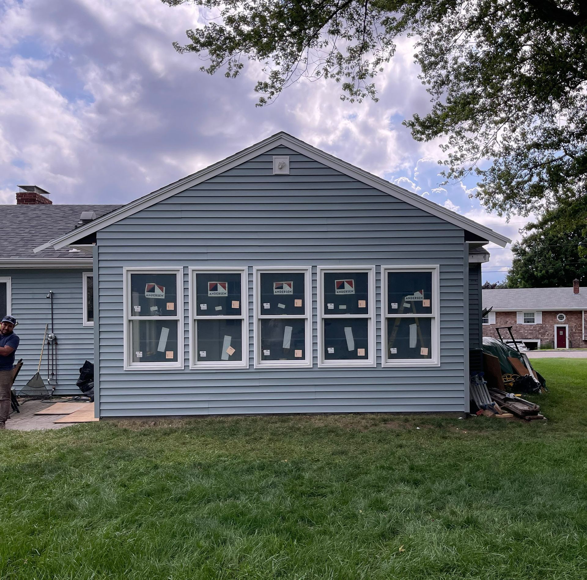 A house with a lot of windows is sitting on top of a lush green field.