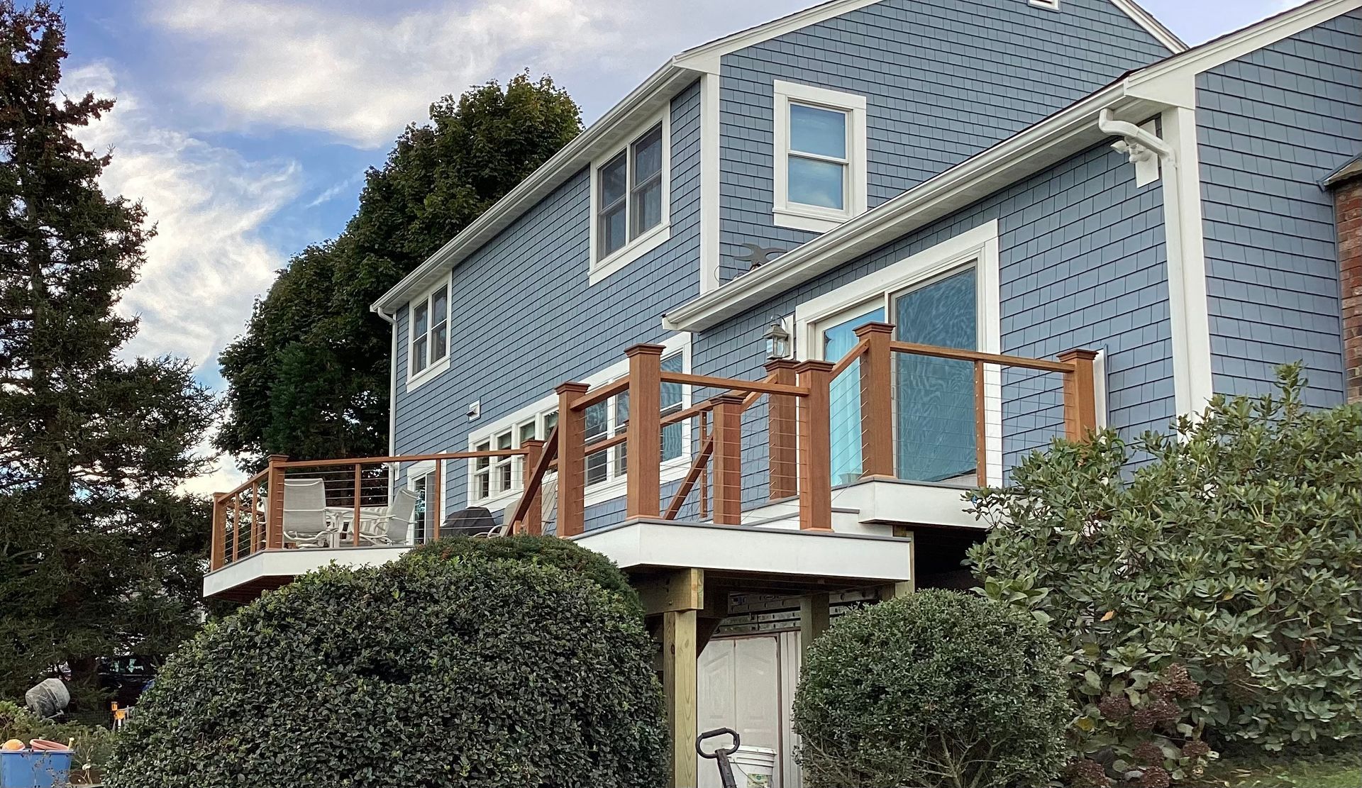 A large blue house with a wooden deck in front of it.