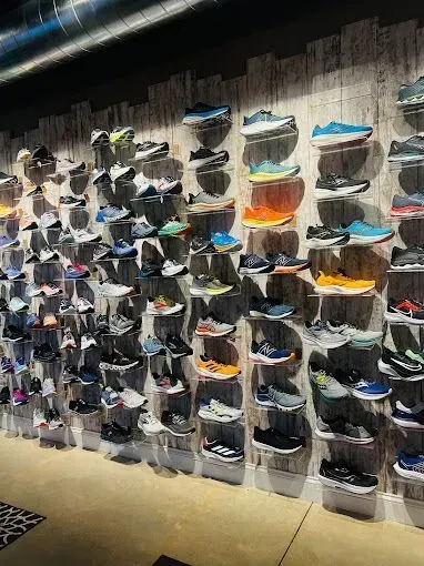 Wall of athletic shoes displayed on clear shelves in a store.