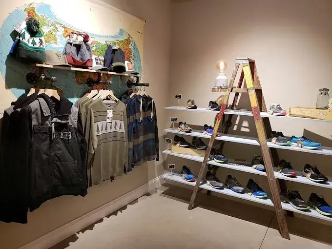 Clothing retail shop with racks of apparel and shelves of shoes, vintage ladder display.