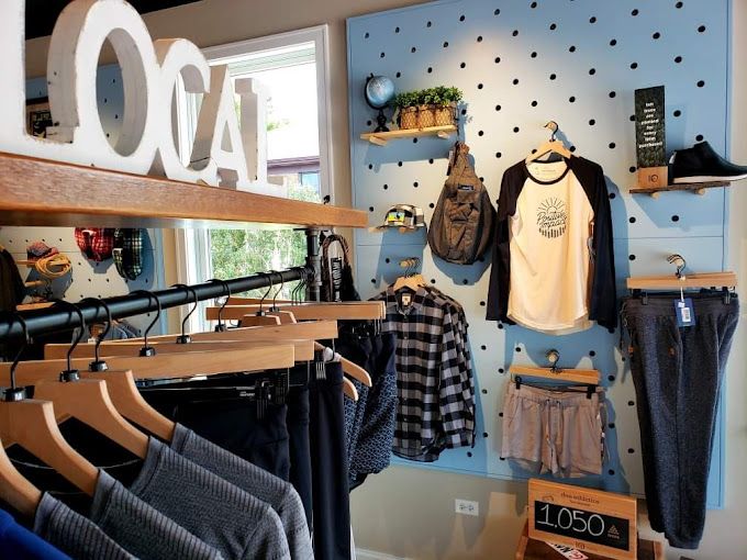 Clothing store interior with clothing racks and merchandise displayed on a blue wall with black dots.