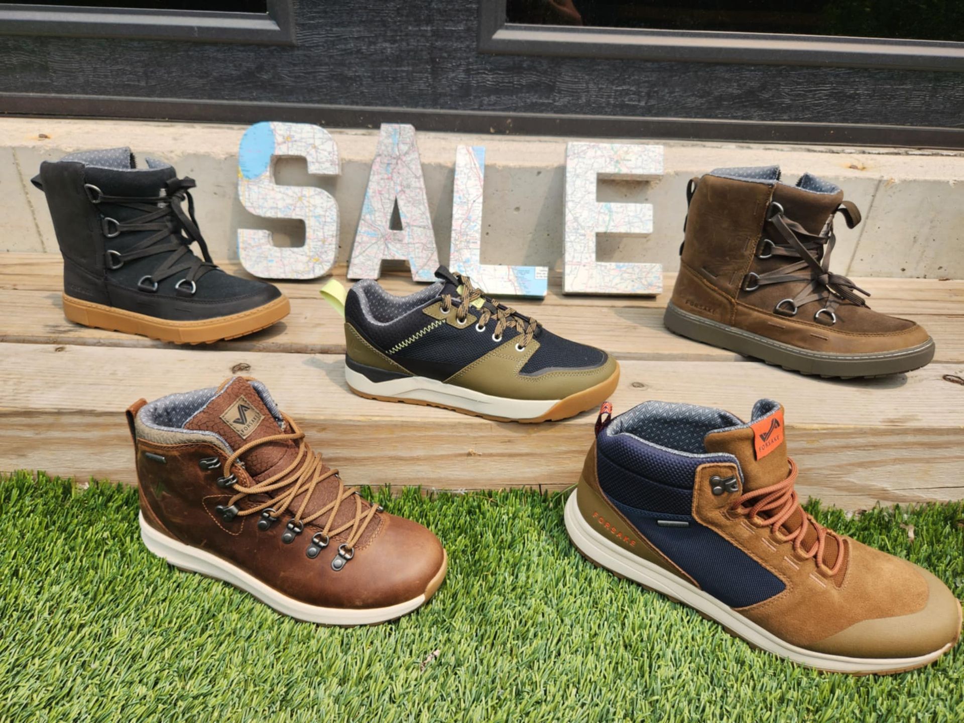 Five pairs of boots and shoes on a grassy area, with a 