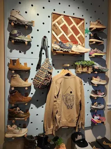 Display wall with shoes, clothing, and bag; pastel blue with black dots, wood accents.