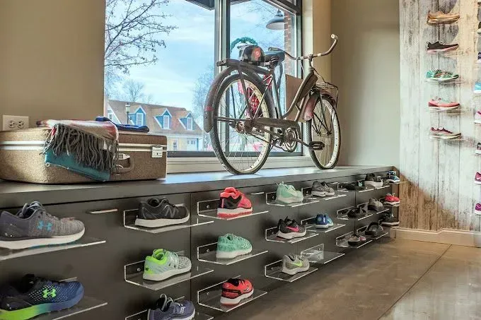 Shoe store interior with display of athletic shoes, vintage bicycle, and window view.
