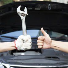 hand holding a wrench and a hand giving thumbs up