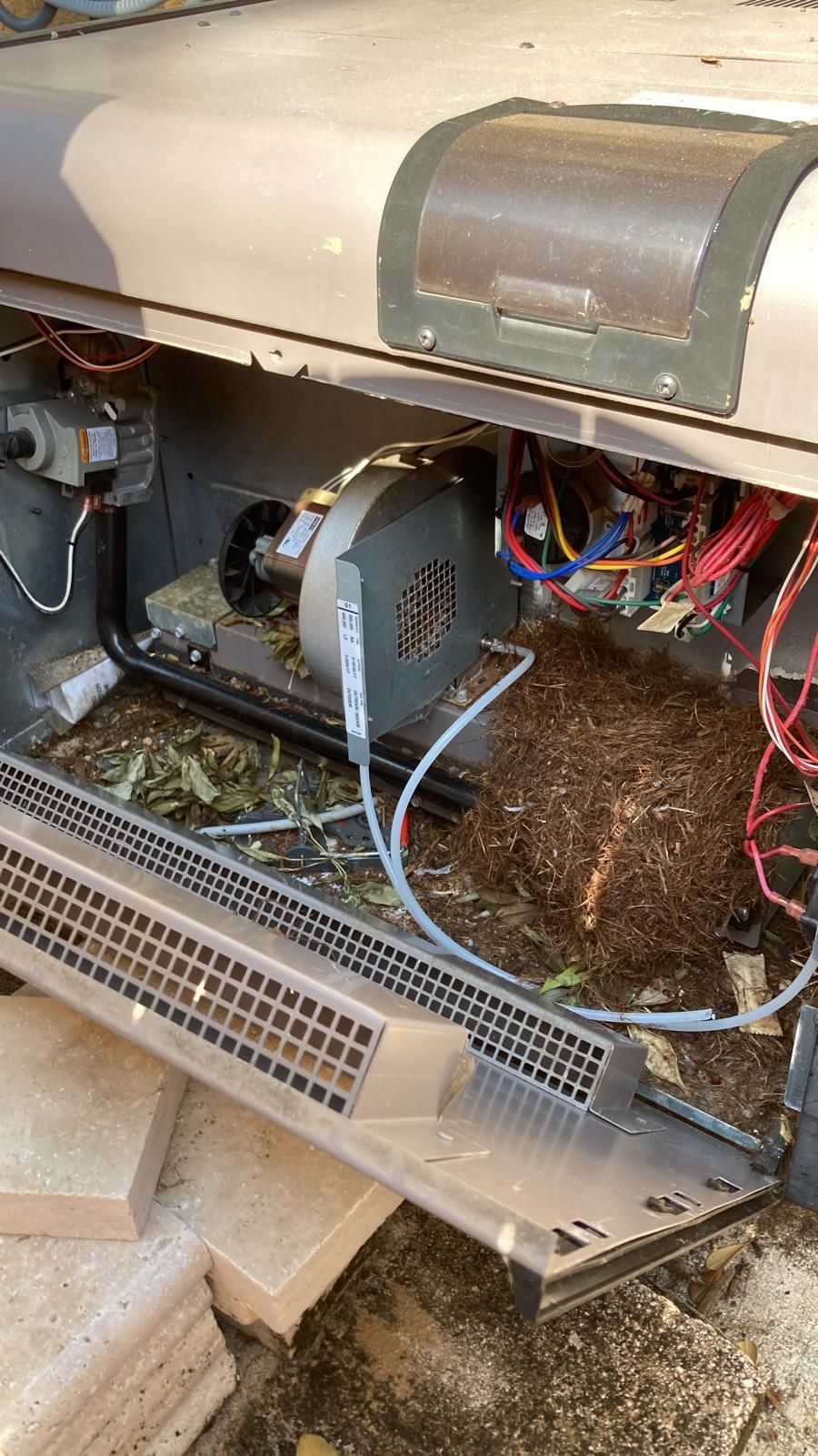 Open air conditioning unit with visible fan, wiring, and debris.