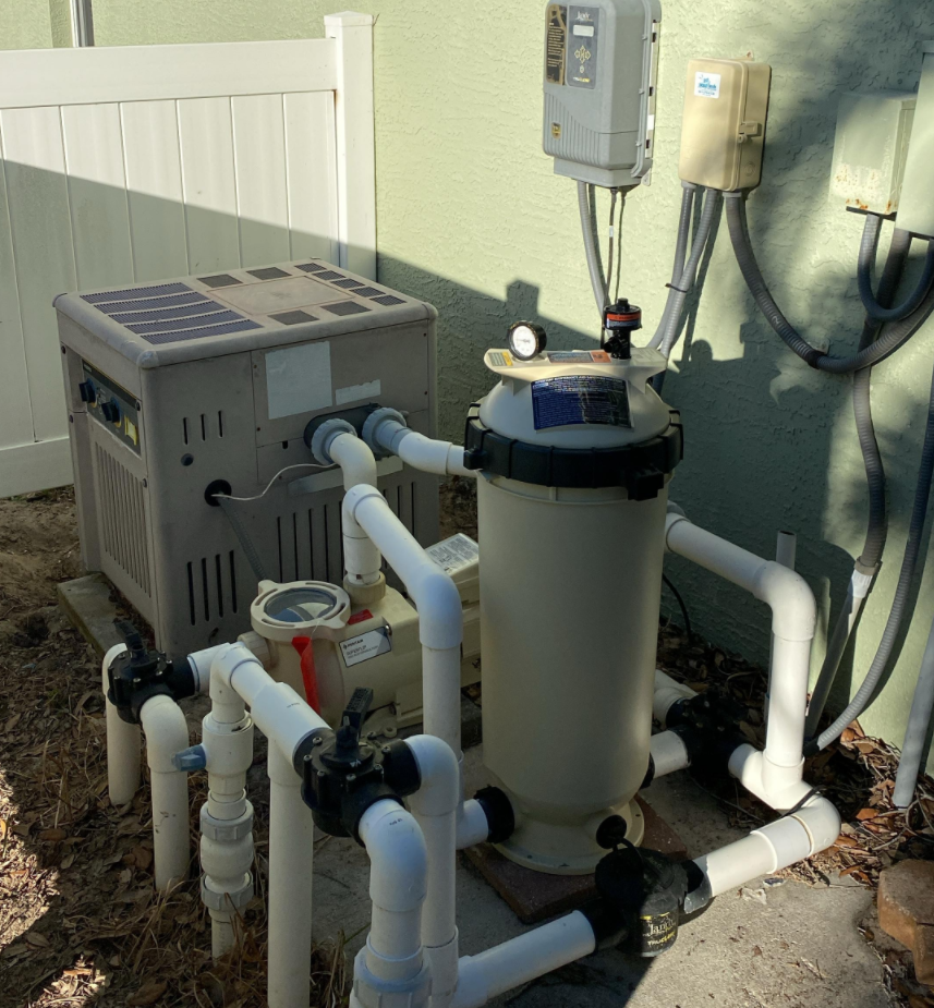 Pool equipment: heater, filter, plumbing, and electrical boxes. Outdoors, near a wall.