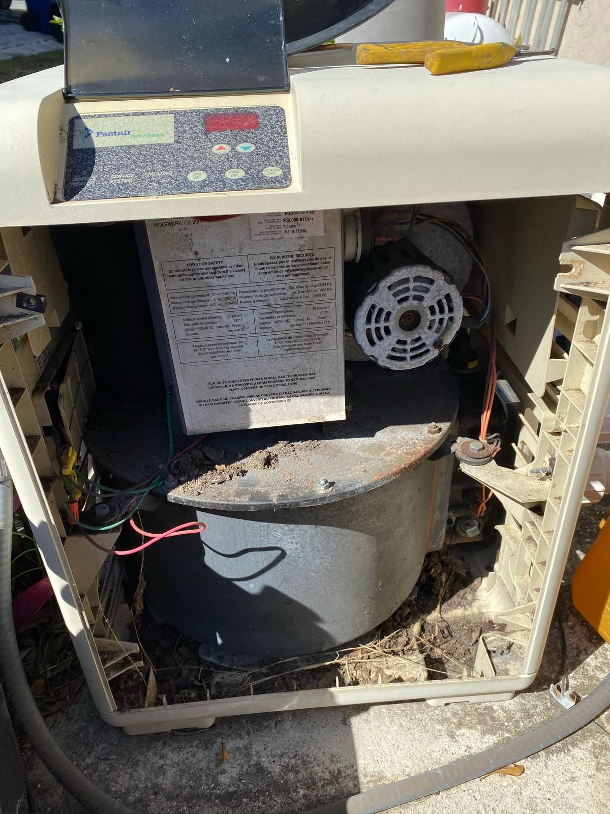 Pool heater with an open side, revealing internal components like a blower and electrical panel.