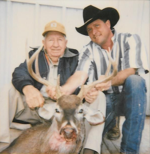 Two men posing with a deer they shot, one wearing a cowboy hat.
