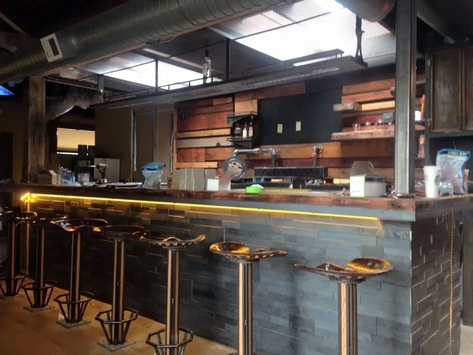 Bar interior with stools, wooden accents, and overhead lighting.